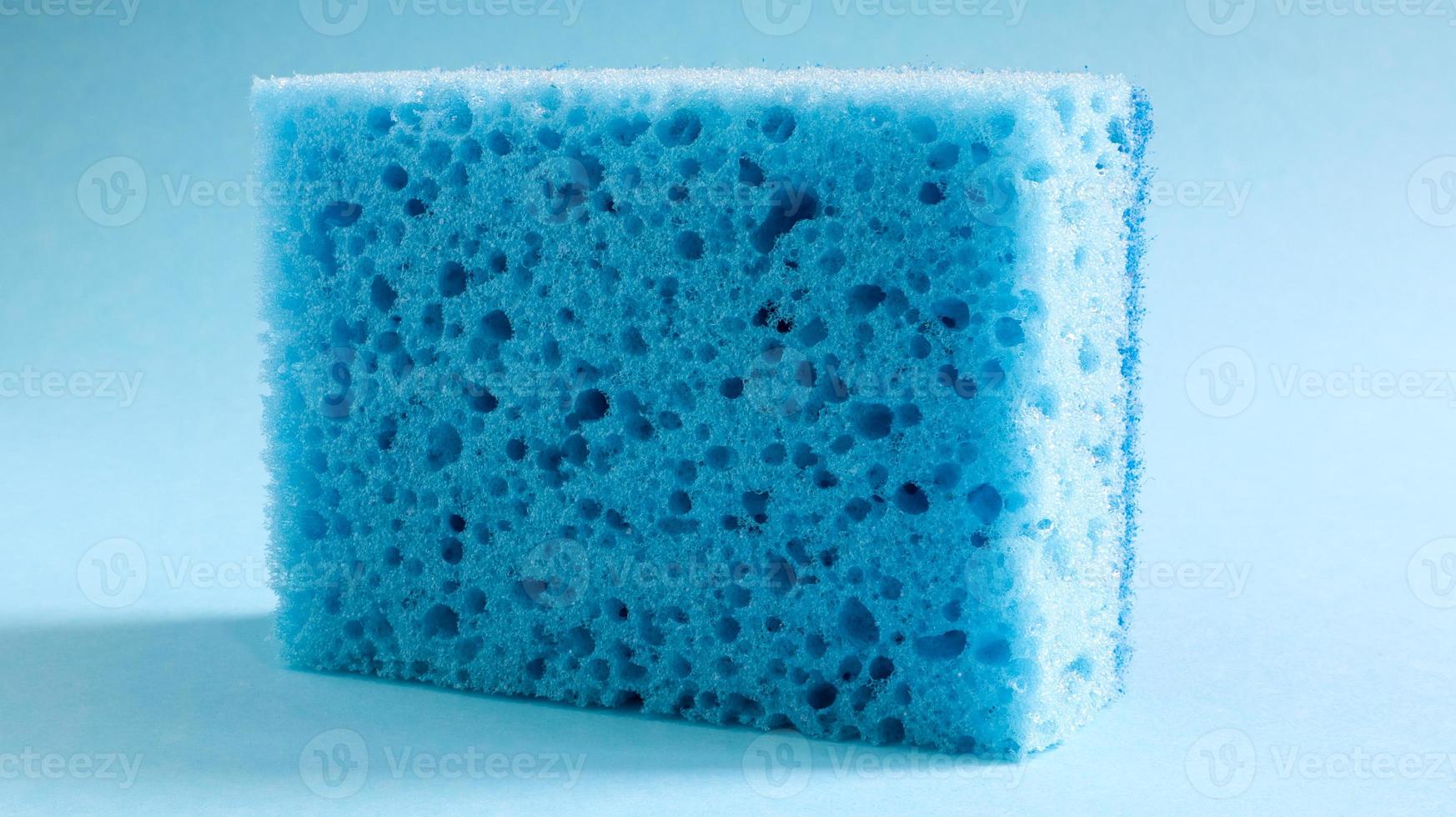 una esponja azul usada para lavar y borrar la suciedad que usan las amas de casa en la vida cotidiana. están hechos de material poroso como la espuma. retención de detergente, que te permite gastarlo económicamente foto