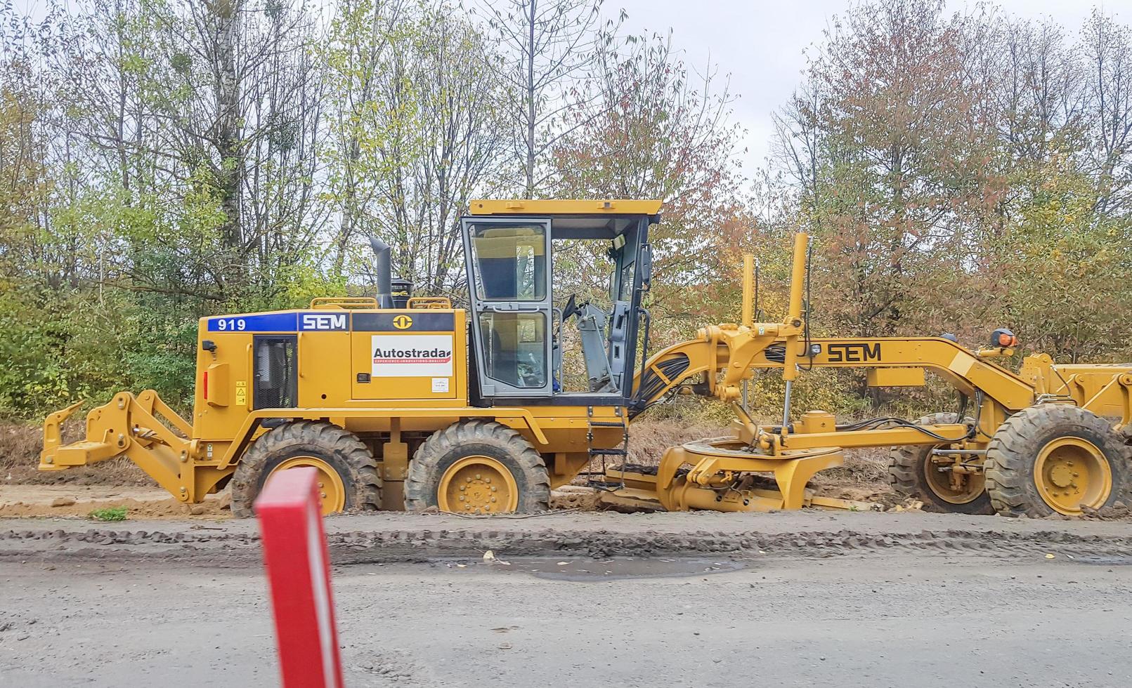 Ukraine, Kiev - October 1, 2019. Road roller, tractor and construction equipment are working on a new road construction site. The road is closed for road repair, route extension, pothole repair photo