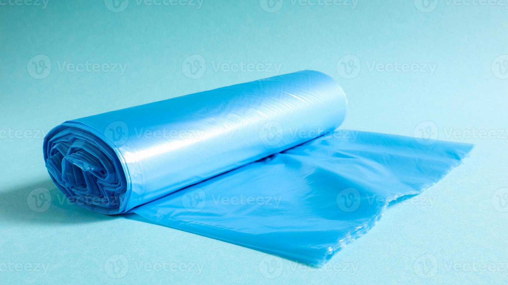One roll of plastic garbage bags in blue on a blue background. Bags that are designed to accommodate garbage in them and used at home and placed in various garbage containers. photo