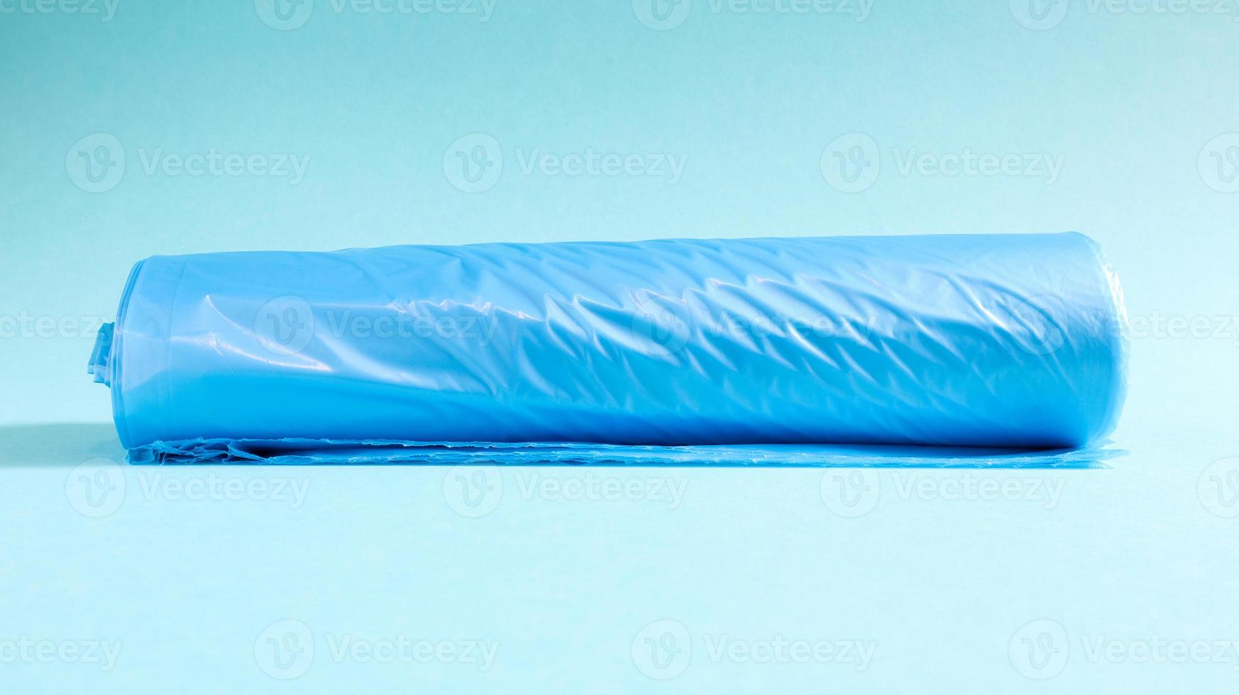 One roll of plastic garbage bags in blue on a blue background. Bags that are designed to accommodate garbage in them and used at home and placed in various garbage containers. photo