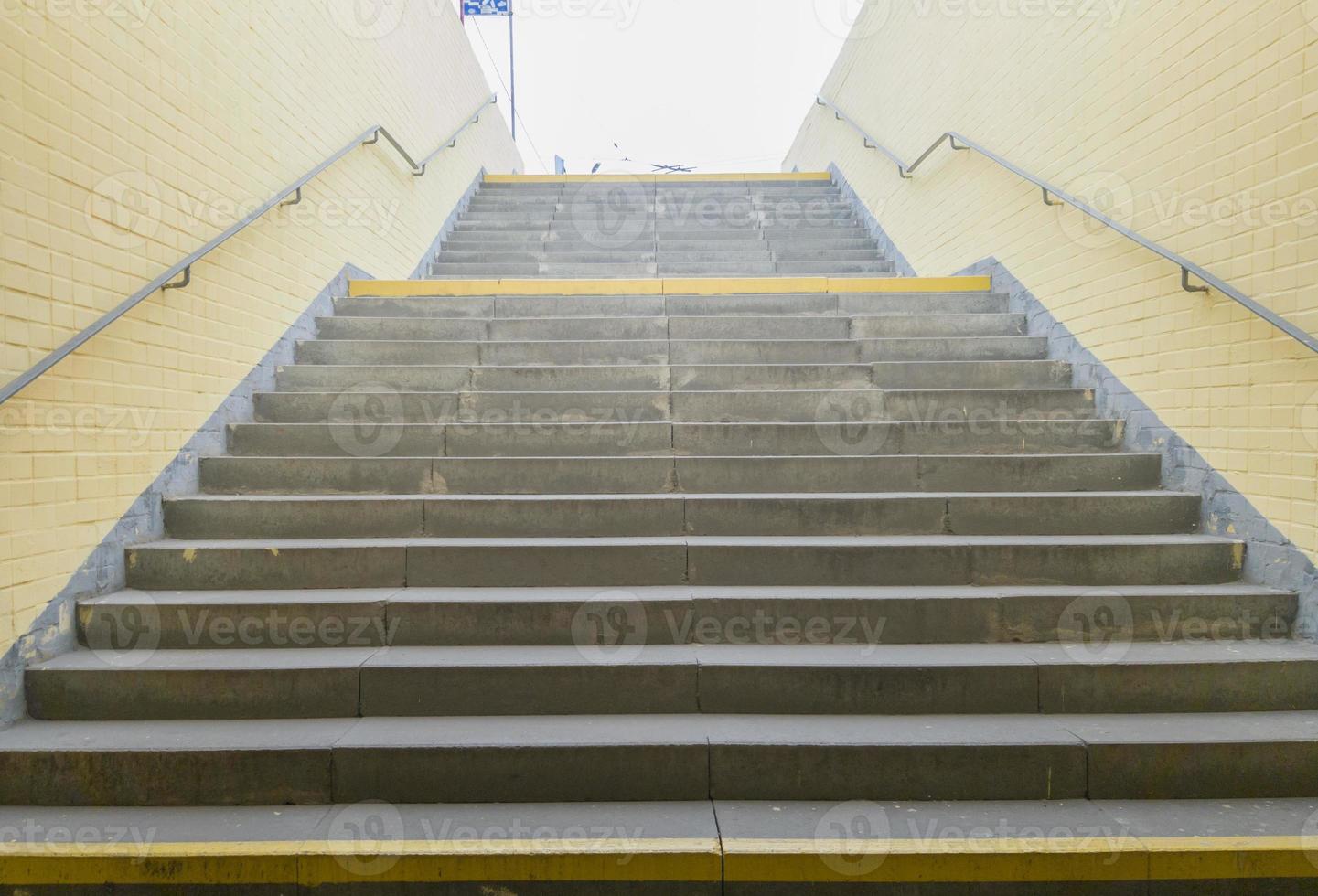 paso de peatones subterráneo amarillo vacío. túnel y luz del día al final. escalones hasta la cima en el paso de peatones. un largo túnel de hormigón con linternas en el metro de la ciudad. foto