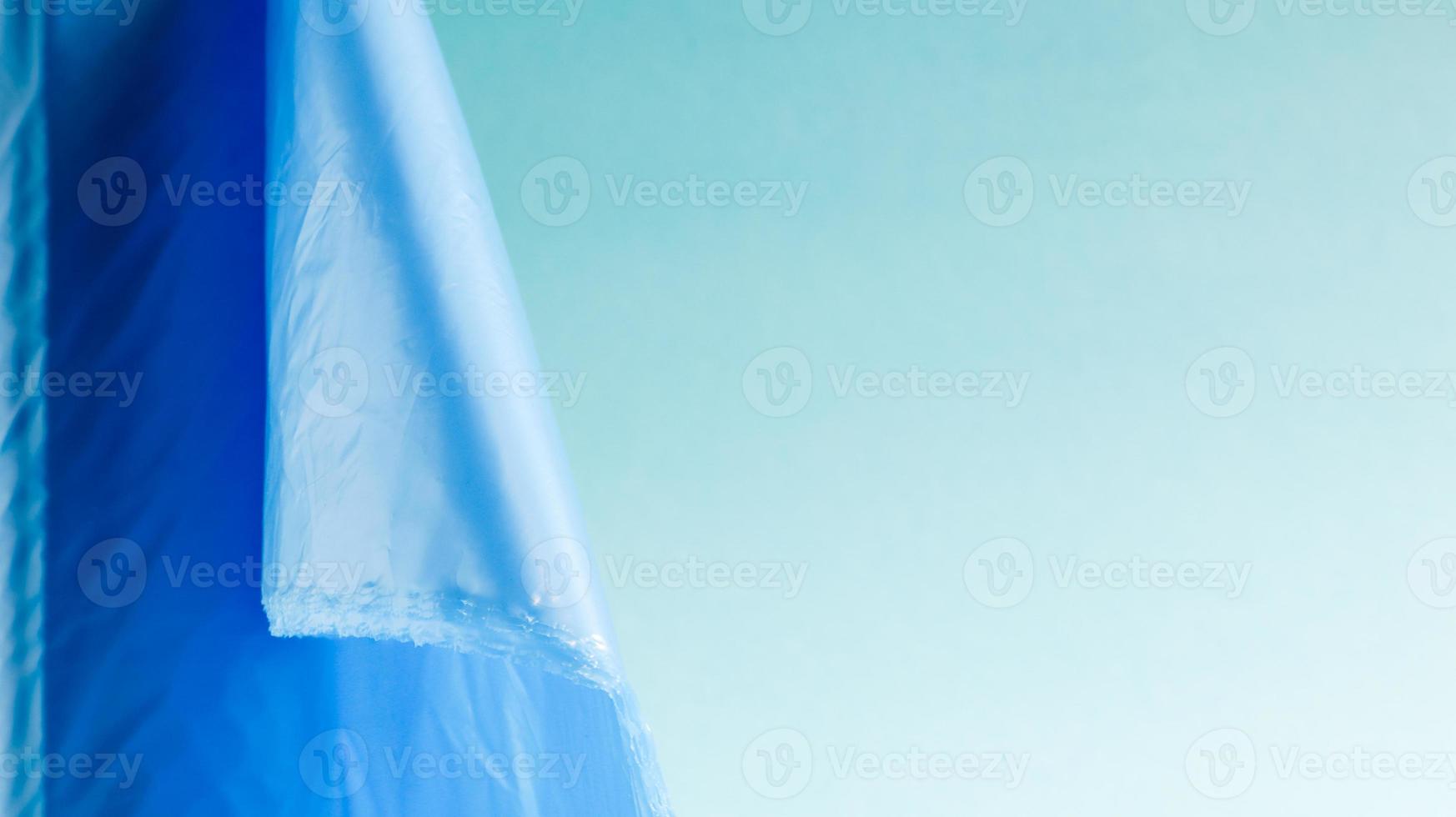 One roll of plastic trash bags in blue on a blue background. Bags that are designed to accommodate garbage in them and used at home and placed in various garbage containers. Copy space photo