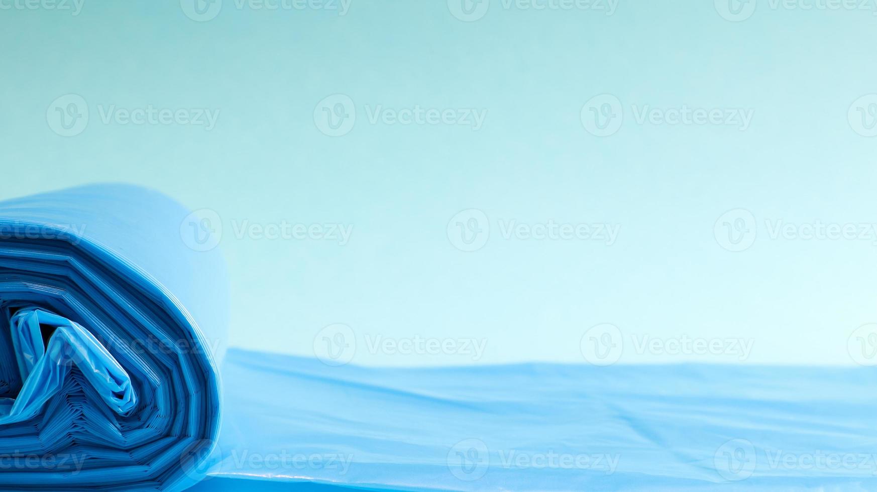 One roll of plastic trash bags in blue on a blue background. Bags that are designed to accommodate garbage in them and used at home and placed in various garbage containers. Copy space photo