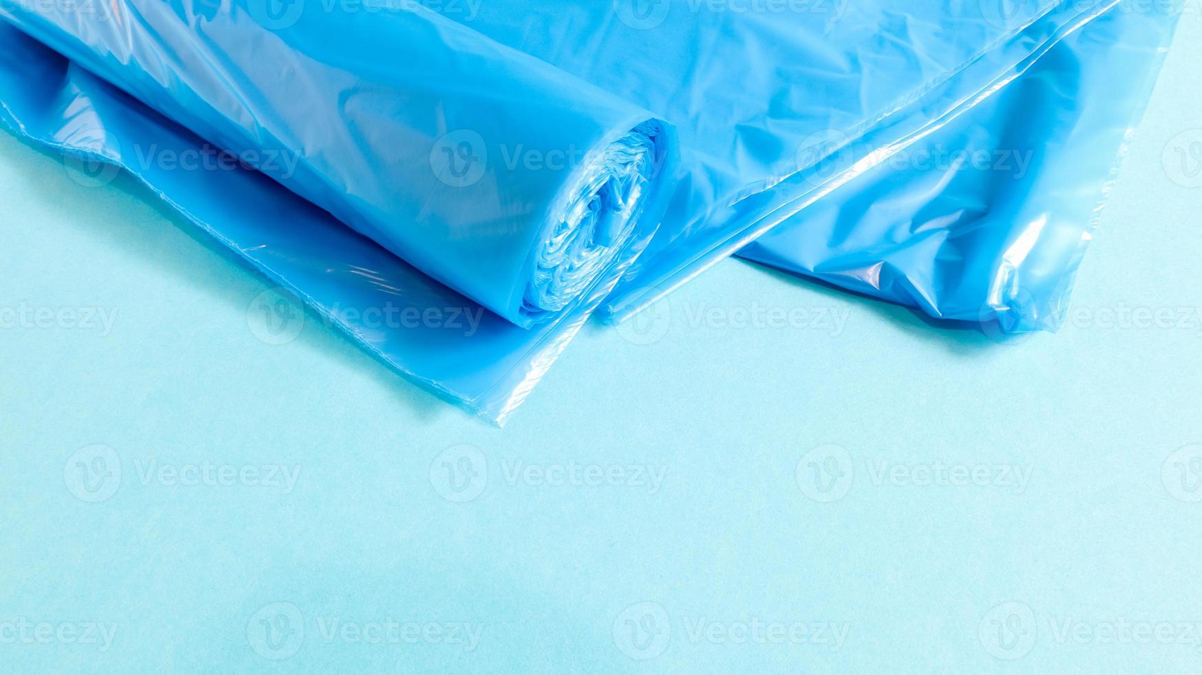 One roll of plastic trash bags in blue on a blue background. Bags that are designed to accommodate garbage in them and used at home and placed in various garbage containers. Copy space photo
