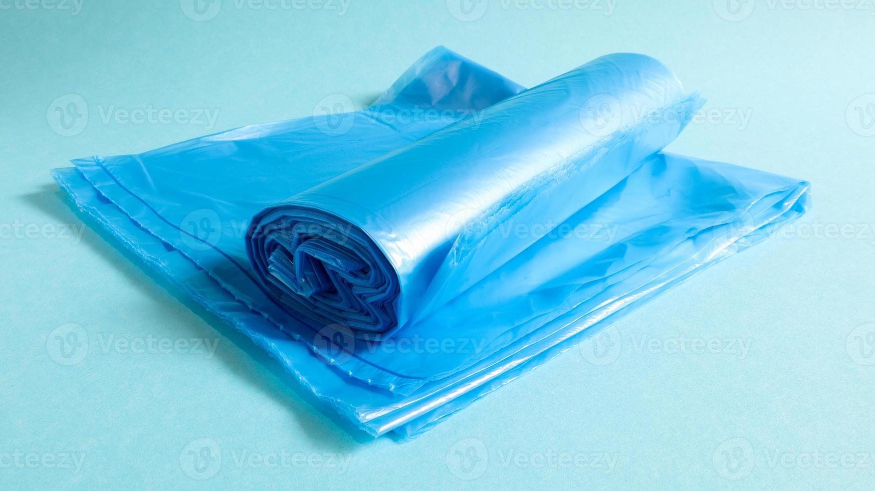 One roll of plastic garbage bags in blue on a blue background. Bags that are designed to accommodate garbage in them and used at home and placed in various garbage containers. photo