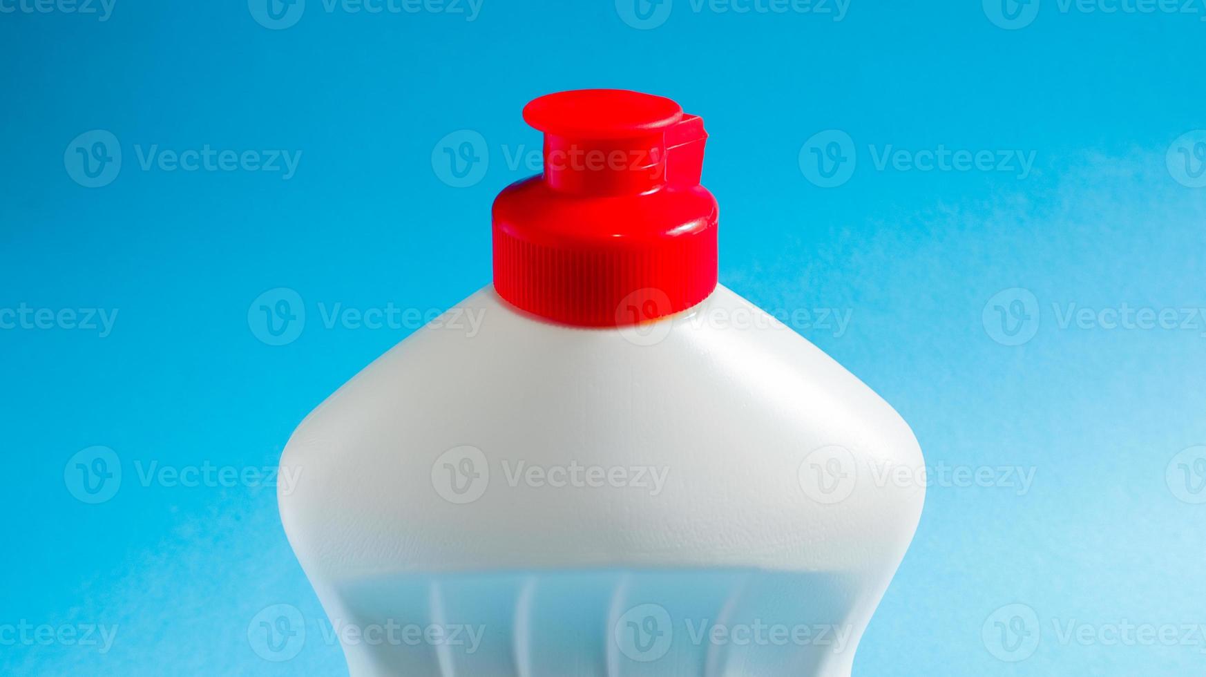 White plastic bottle with dishwashing detergent, bleach or fabric softener on a blue background. liquid washing powder. The concept of cleaning. photo