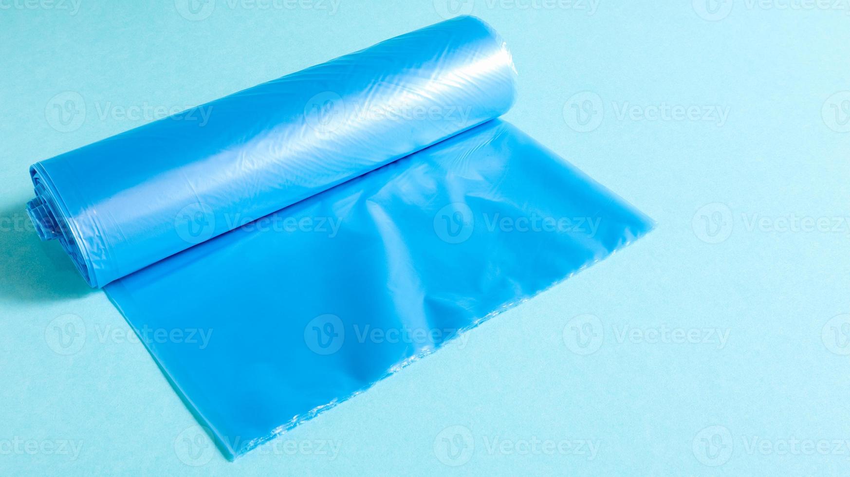 One roll of plastic garbage bags in blue on a blue background. Bags that are designed to accommodate garbage in them and used at home and placed in various garbage containers. photo