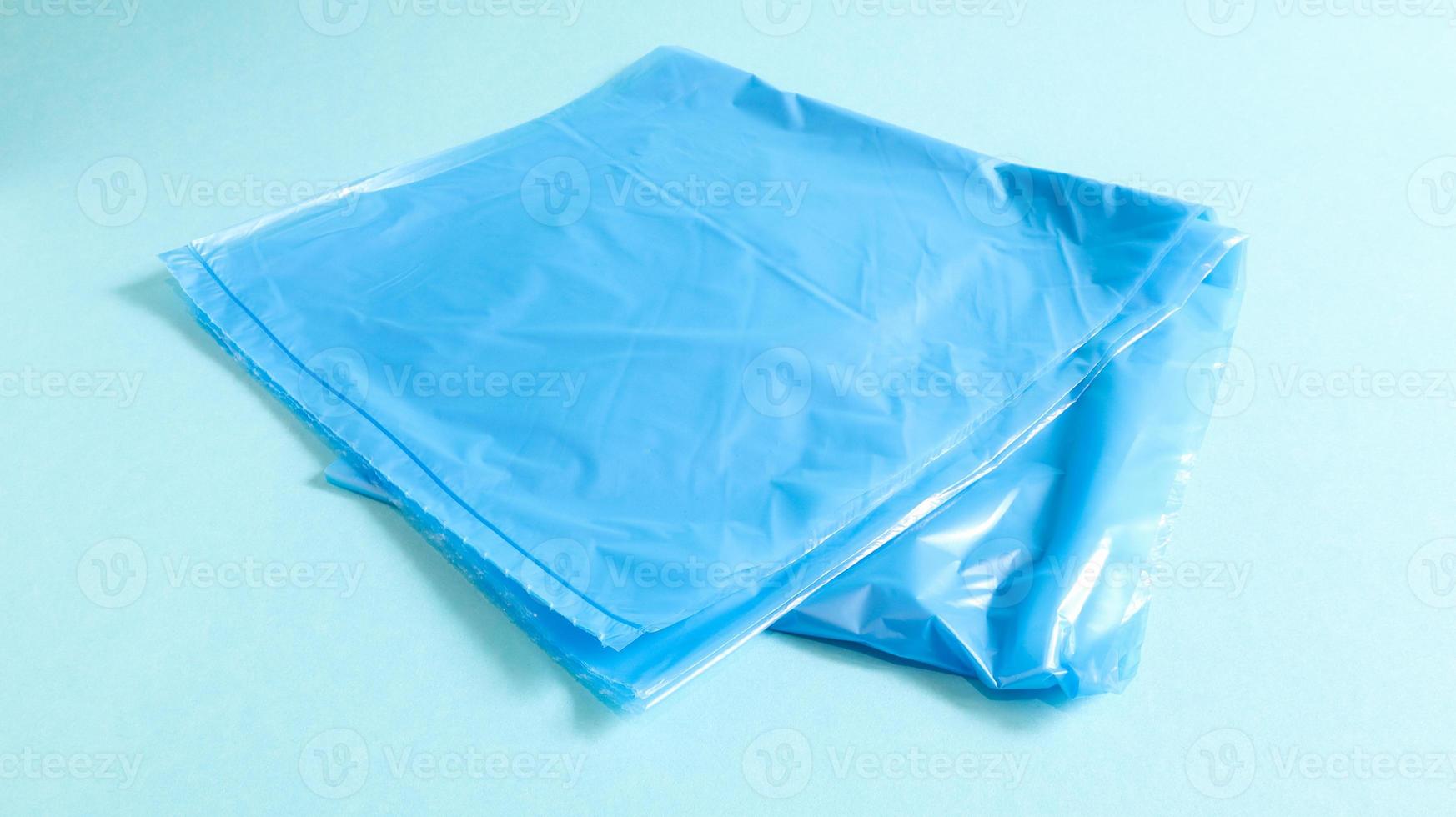 One torn plastic garbage bag in blue on a blue background. A bag that is designed to accommodate garbage in it and is used at home and placed in various garbage containers. photo
