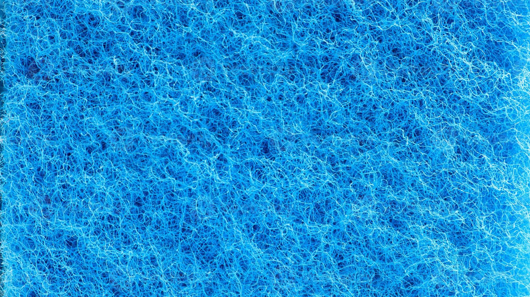 Background in the form of a porous structure in blue. Macro sponge. Close up blue sponge surface for textured background. copy space. photo