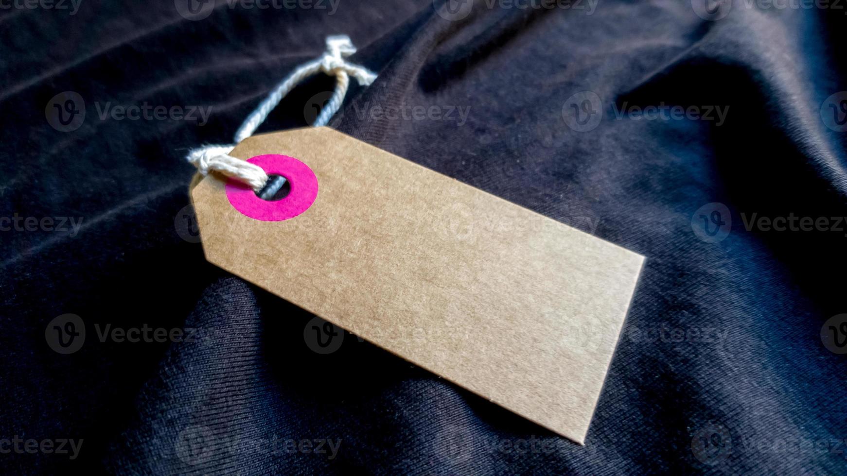 brown cardboard label with a thin cord on a black fabric background. Background, holiday concept. Black Friday - International Day of Shopping, Promotions, Discounts, Sales. photo