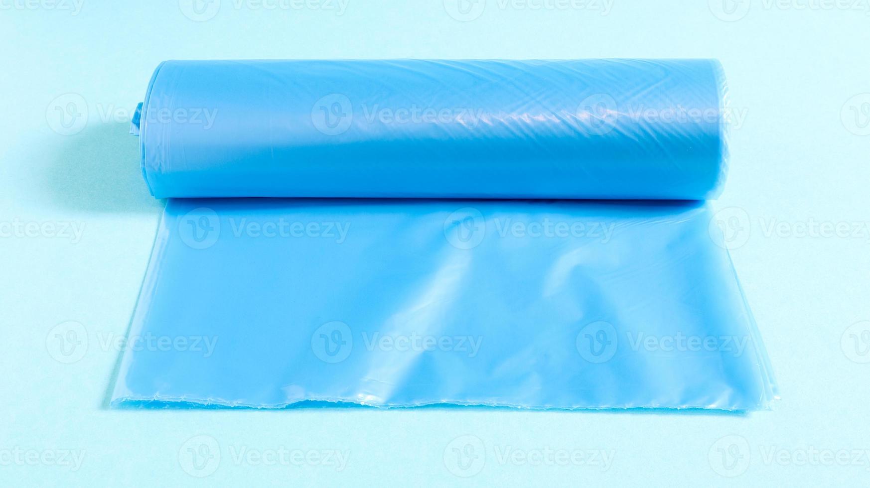 One roll of plastic garbage bags in blue on a blue background. Bags that are designed to accommodate garbage in them and used at home and placed in various garbage containers. photo