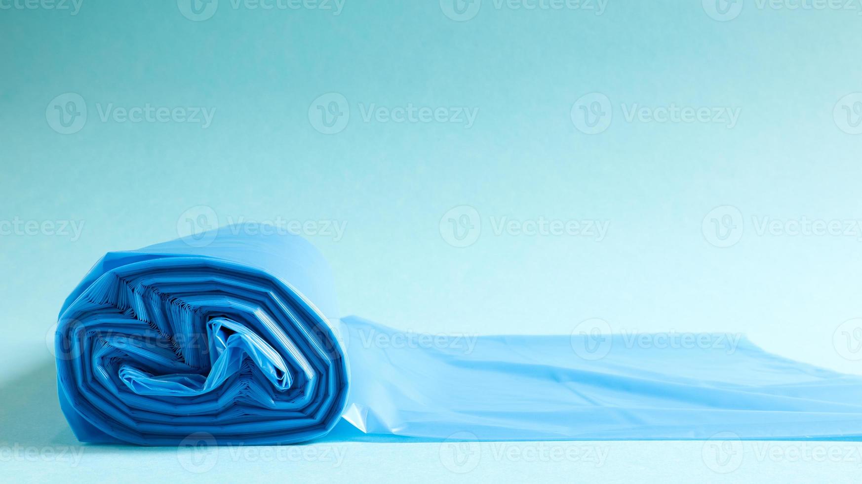 One roll of plastic trash bags in blue on a blue background. Bags that are designed to accommodate garbage in them and used at home and placed in various garbage containers. Copy space photo