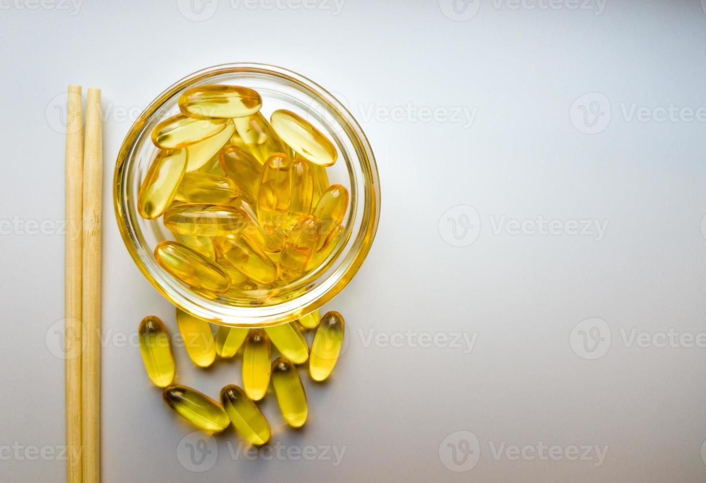 Fish oil capsules on a saucer with chopsticks. Bunch of vitamin omega 3 pills on a white background. Close-up, top view, high resolution product. Metabolism in the body. Body calcium. photo