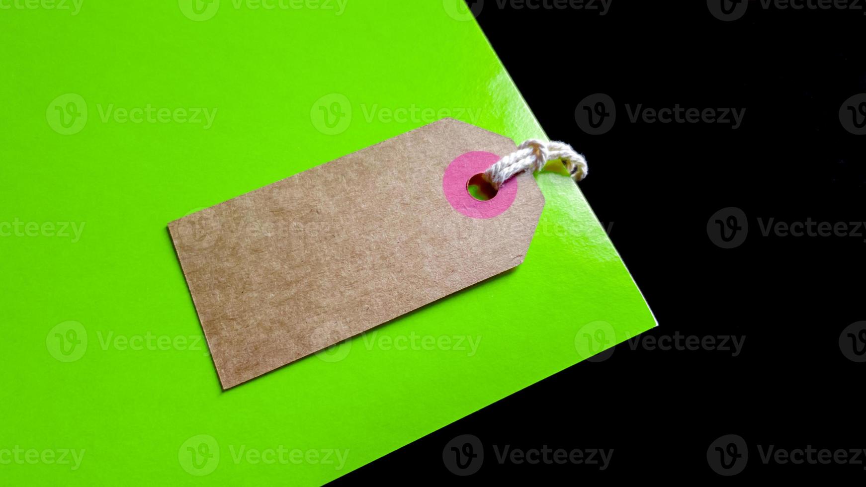 Blank brown cardboard price tag or label on green and black background. view from above photo