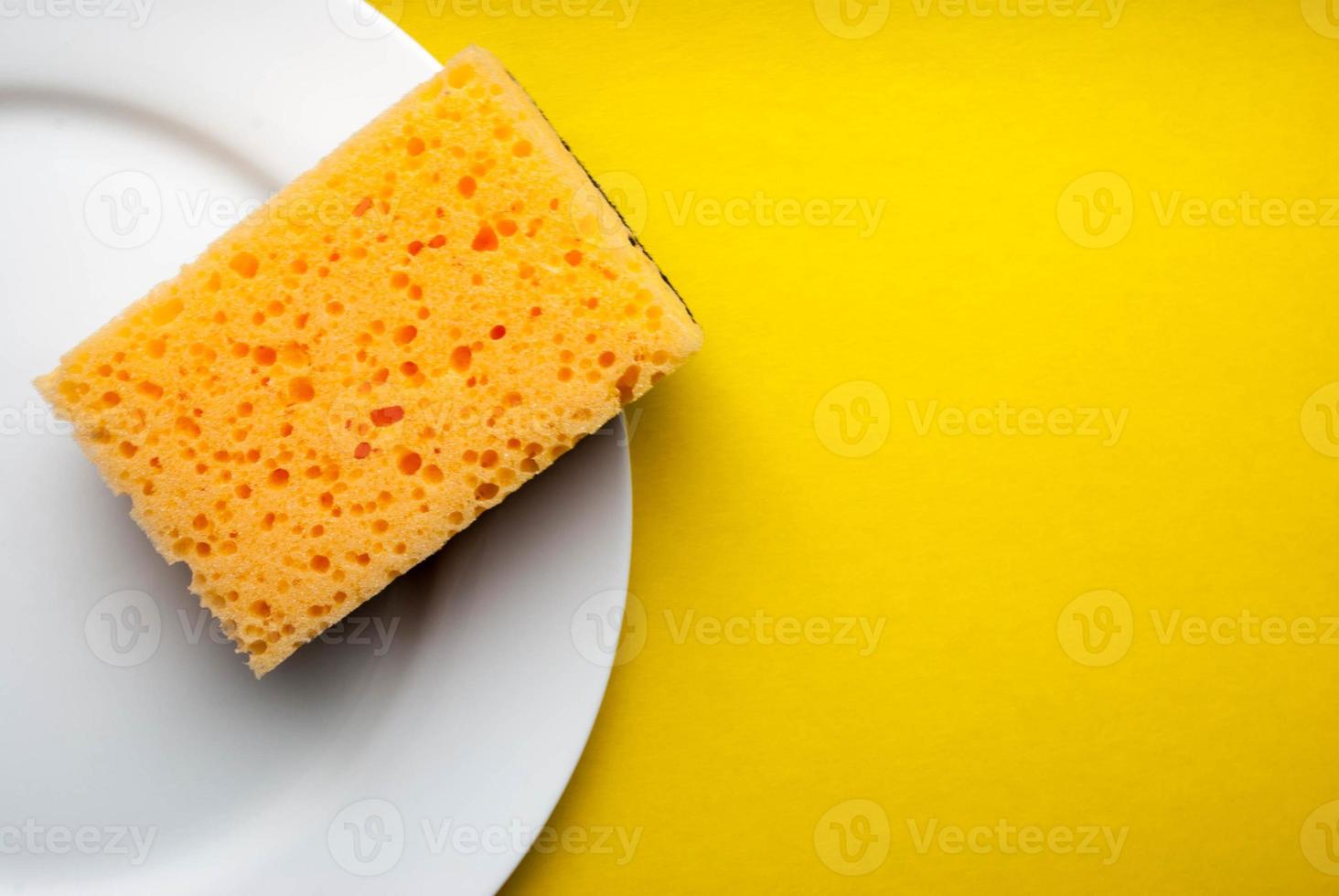 Cleaning sponge on a white plate on a yellow background photo