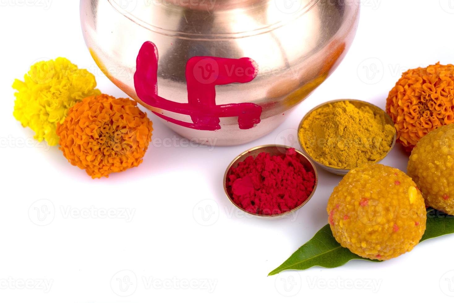 kalash de cobre con coco, hoja de mango, haldi, kumkum y dulces con decoración de flores de caléndula sobre un fondo blanco. esencial en puja hindú. foto