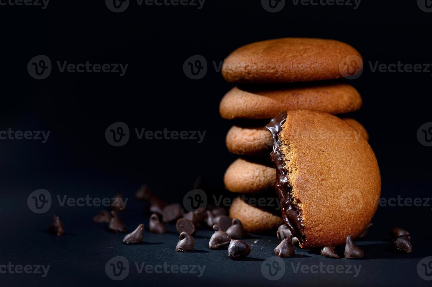 BISCUITS - Stack of delicious cream biscuits filled with chocolate cream on black background photo