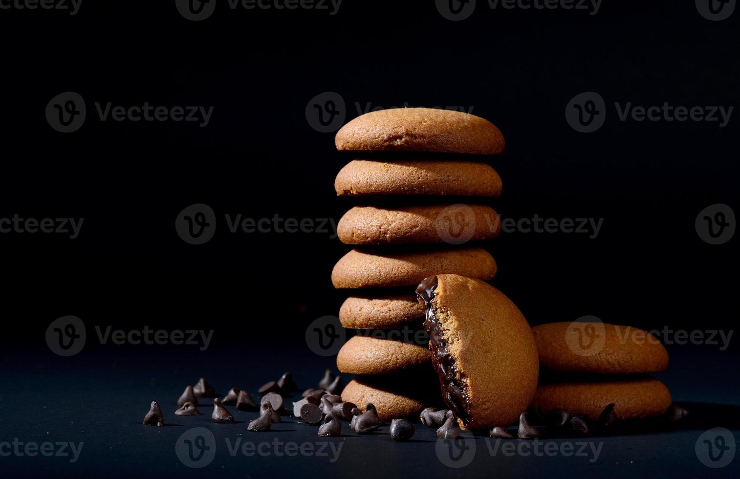 BISCUITS - Stack of delicious cream biscuits filled with chocolate cream on black background photo