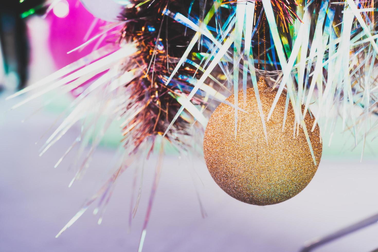 Golden glitter Christmas ball hung on beautiful rainbow Christmas tree. Empty space for entering text. New Year's Eve Festival. photo