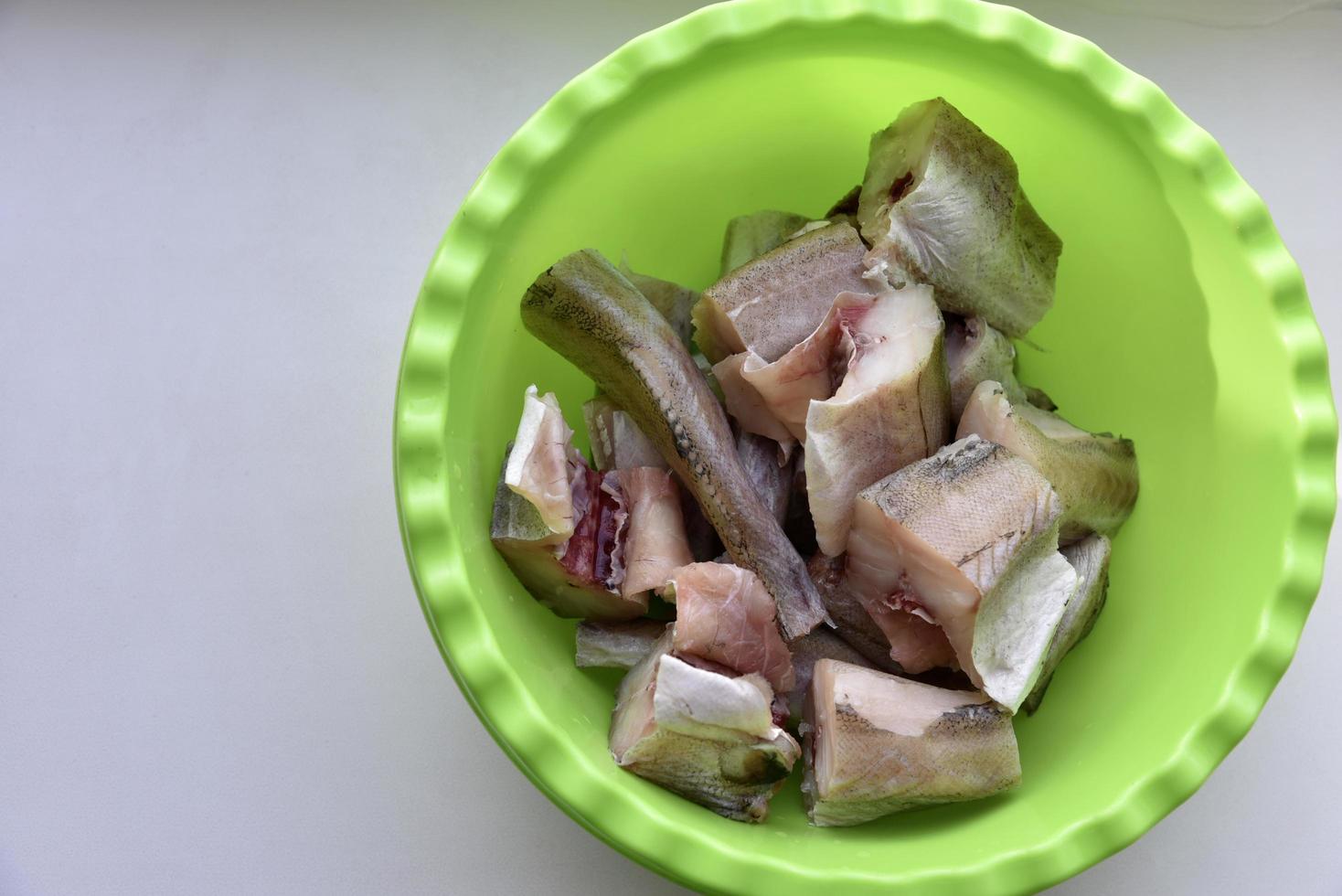 Freshly cleaned pollock fish in a green plate photo