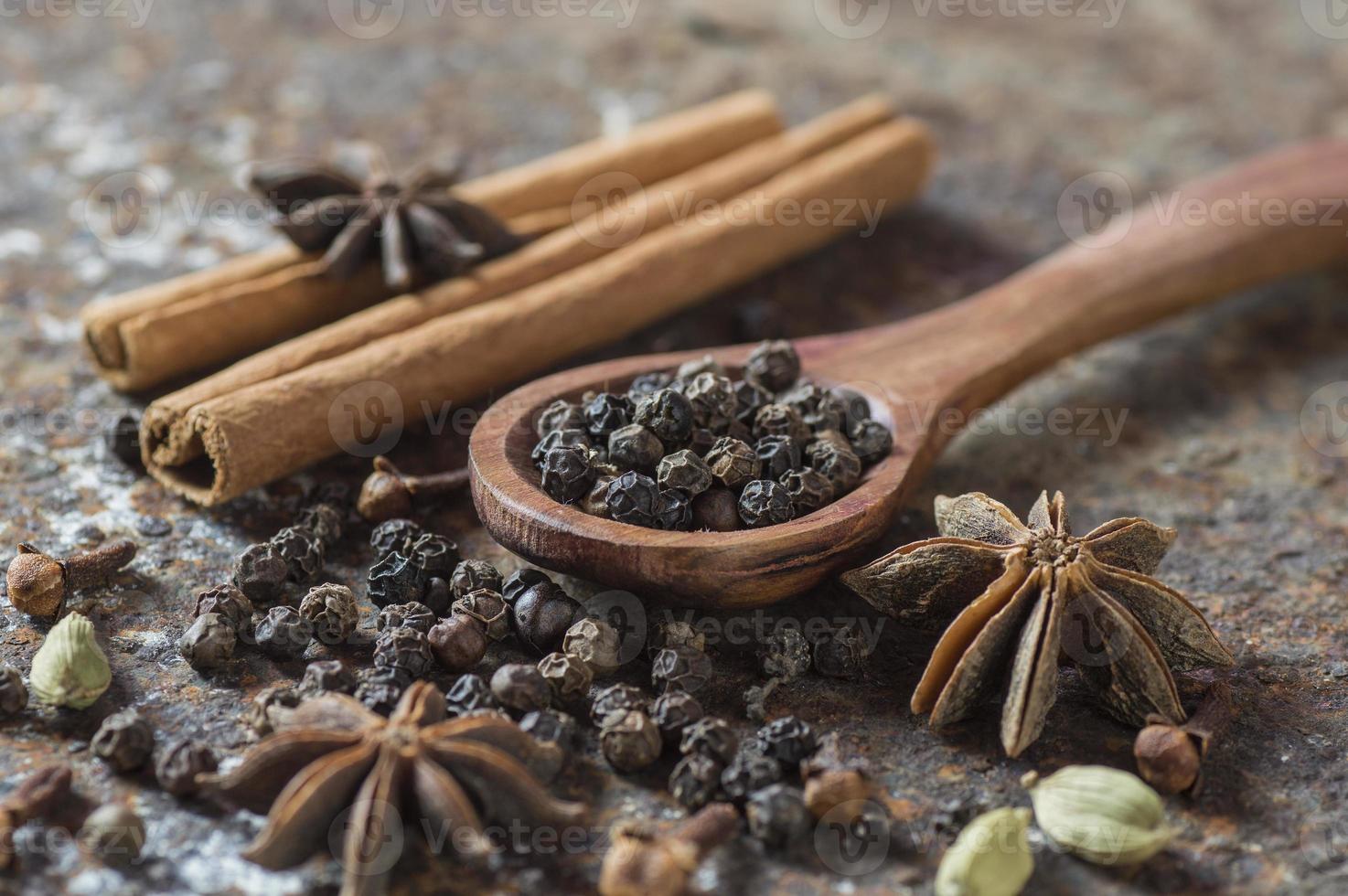 especias y hierbas. ingredientes de la comida y la cocina. palitos de canela, estrellas de anís, pimienta negra y cardamomo sobre un fondo texturizado. foto