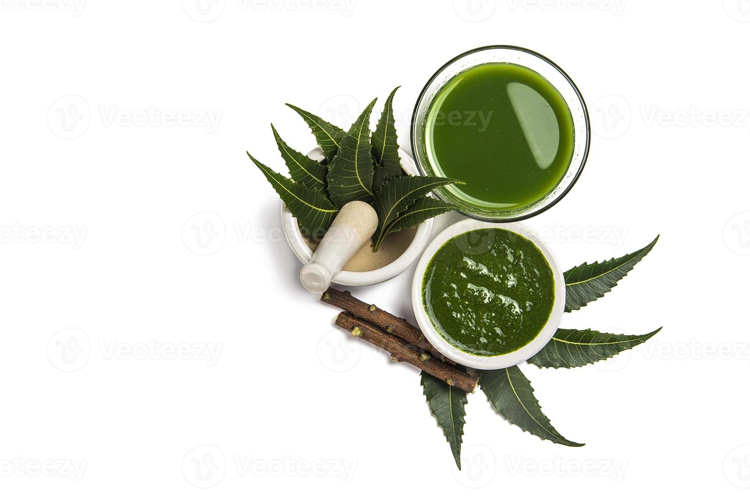 Medicinal Neem leaves in mortar and pestle with neem paste, juice and twigs on white background photo