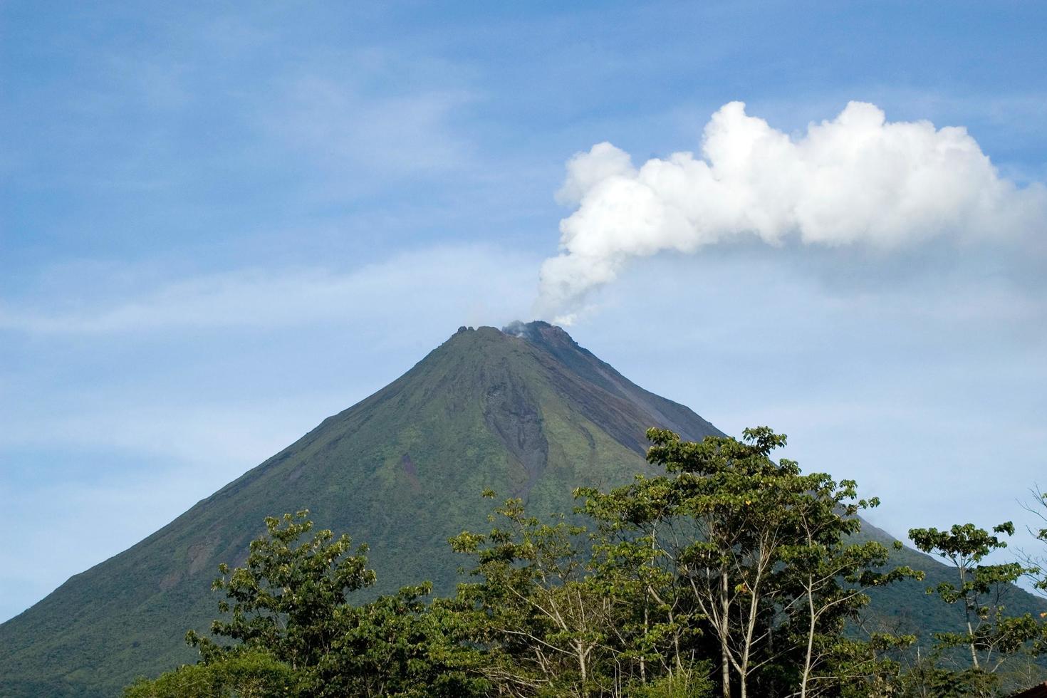 vista panorámica del volcán arenal, en alajuela, costa rica. humo saliendo del cráter. sin gente, día soleado. foto