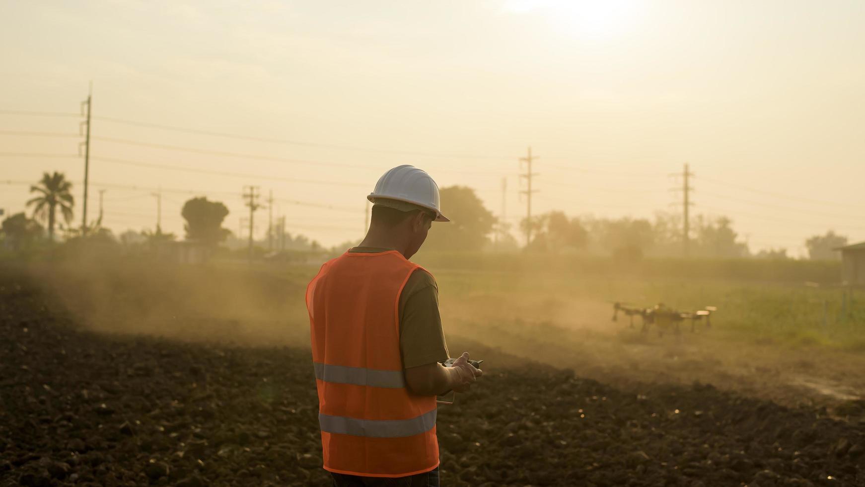 Male engineer controlling drone spraying fertilizer and pesticide over farmland,High technology innovations and smart farming photo