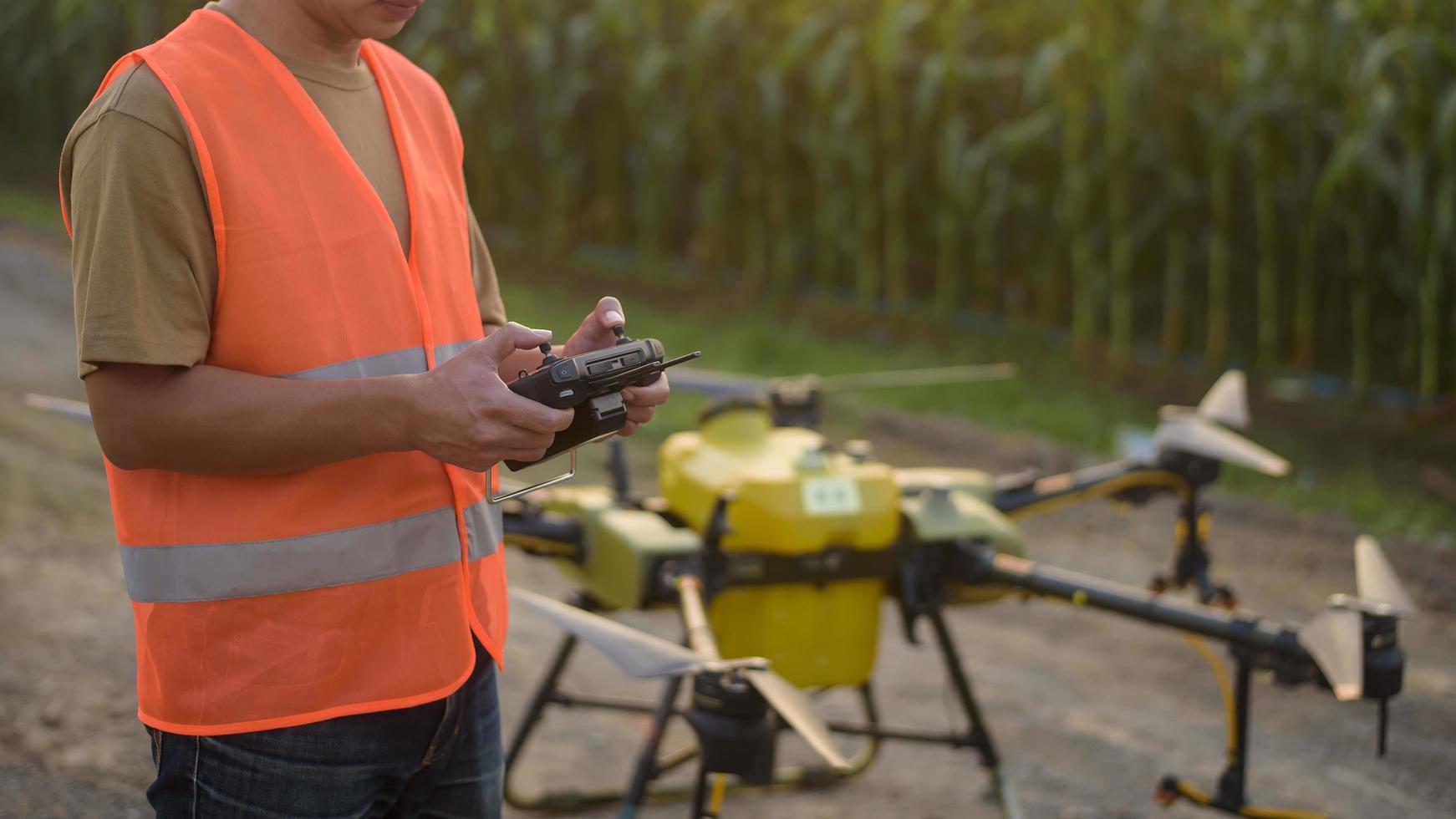 Male engineer controlling drone spraying fertilizer and pesticide over farmland,High technology innovations and smart farming photo