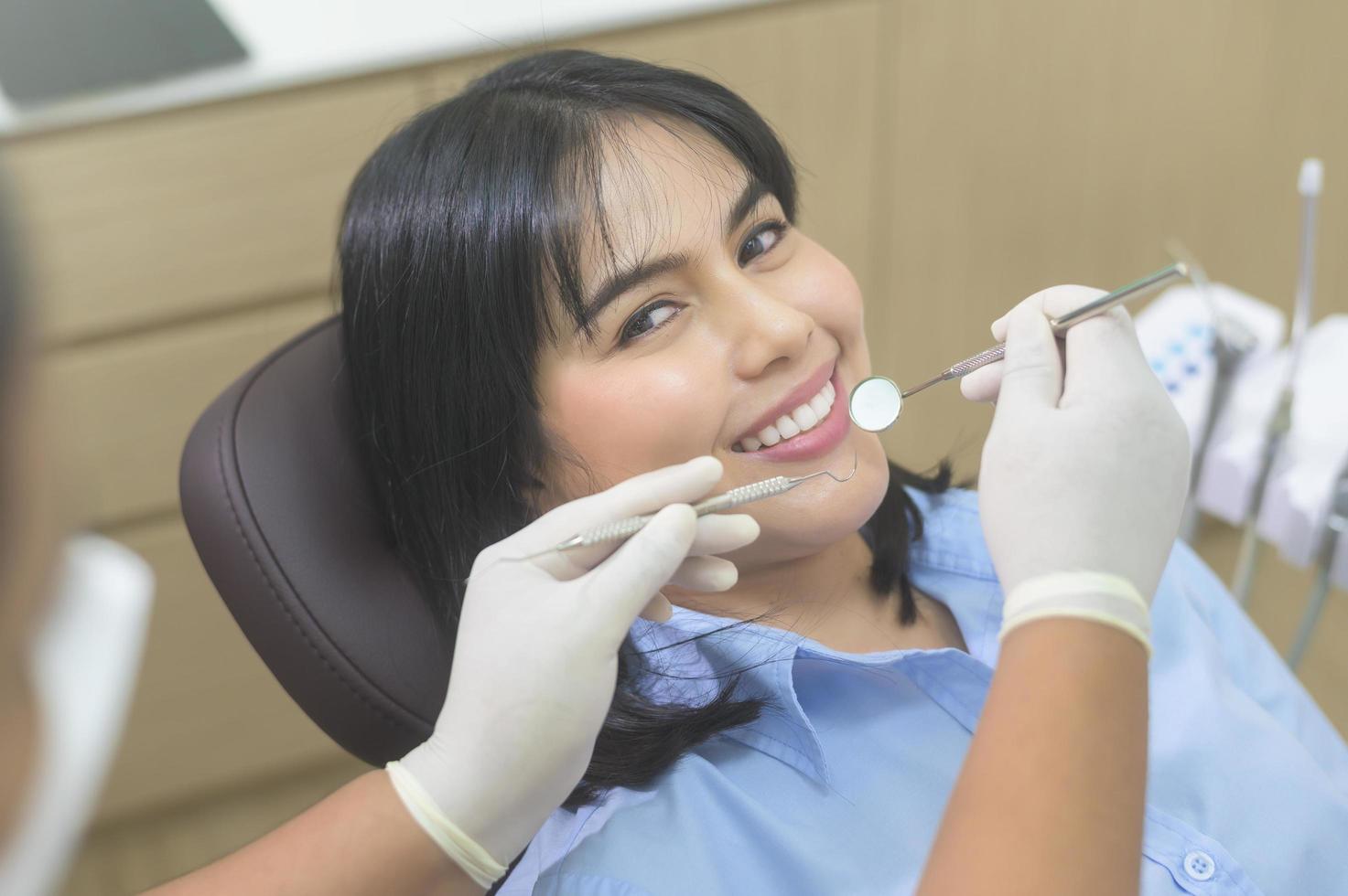 mujer joven con dientes examinados por dentista en clínica dental, revisión de dientes y concepto de dientes sanos foto