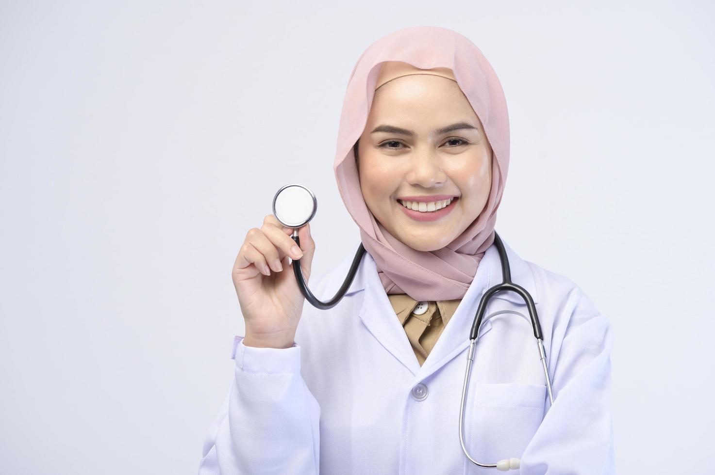 Female muslim doctor with hijab over white background studio. photo