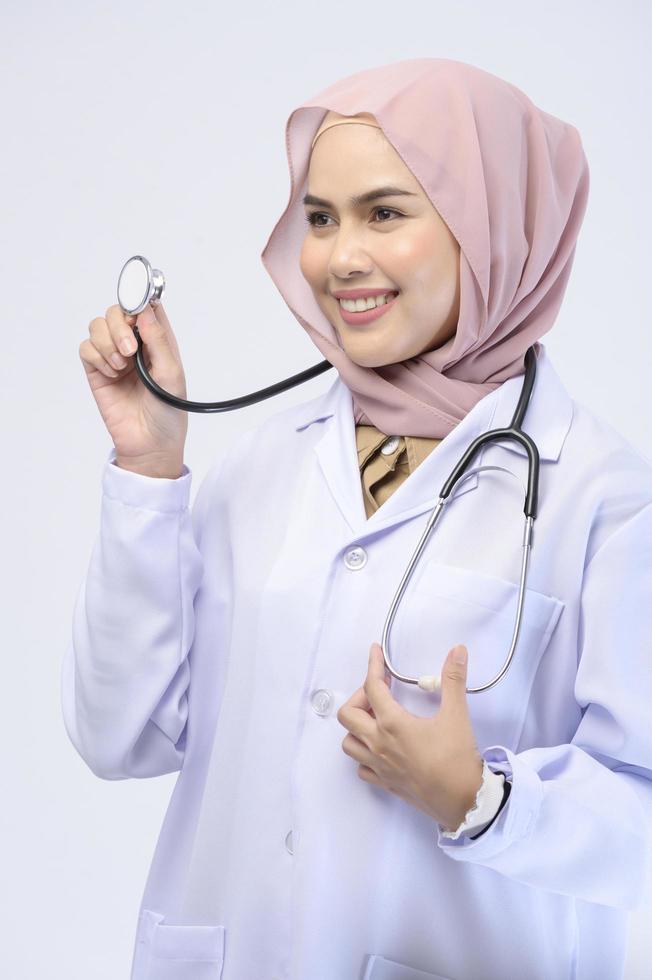 Female muslim doctor with hijab over white background studio. photo