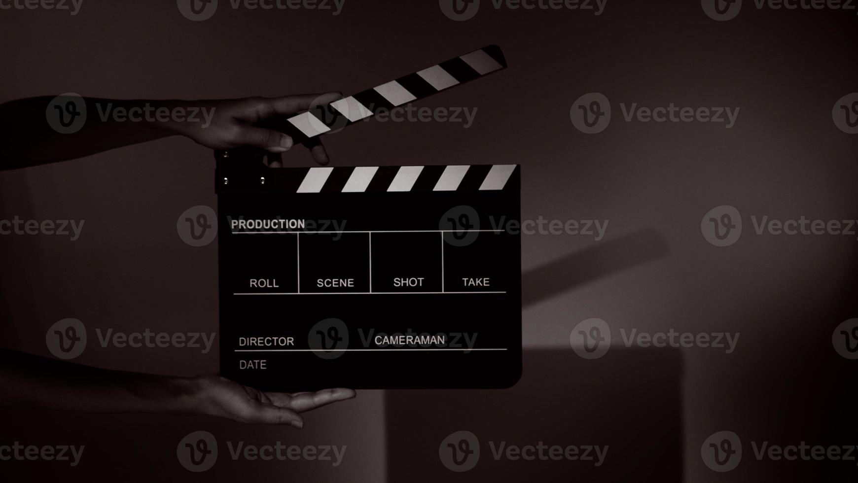 Hand holds empty film making clapperboard on color background in studio photo