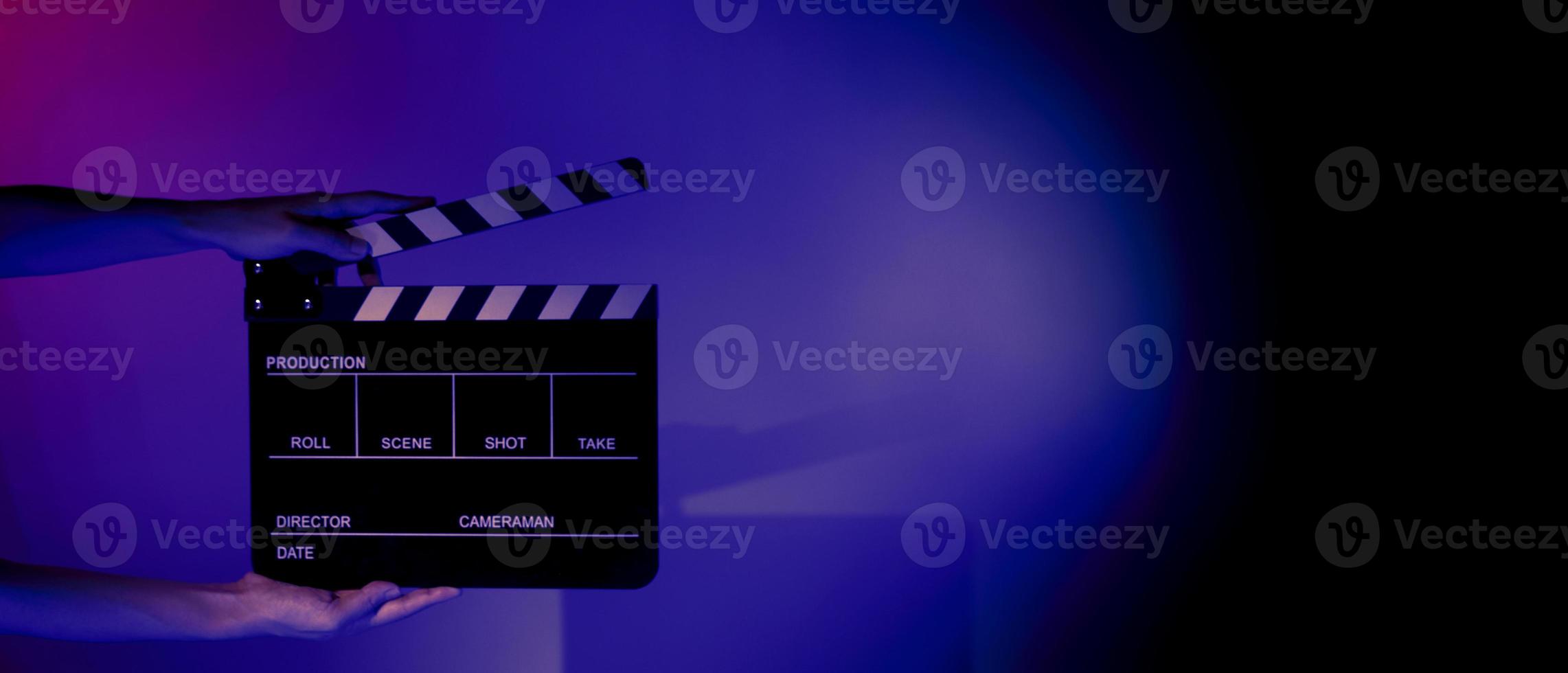 Hand holds empty film making clapperboard on color background in studio photo