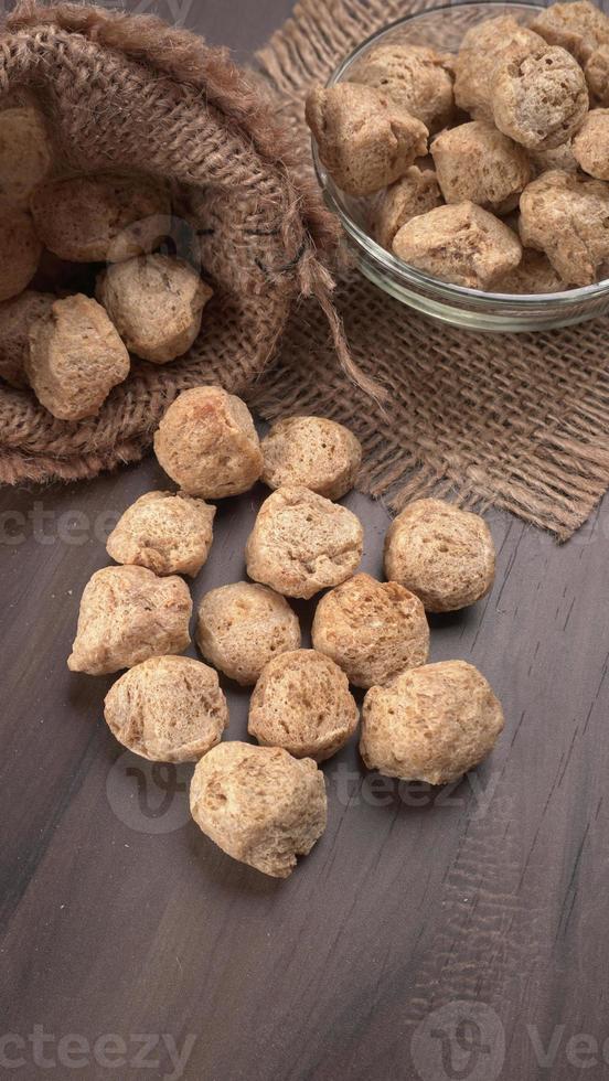 Raw soya chunks on dark background. Healthy, nutritious soybean meat, chunks isolated.Vegan food concept. photo