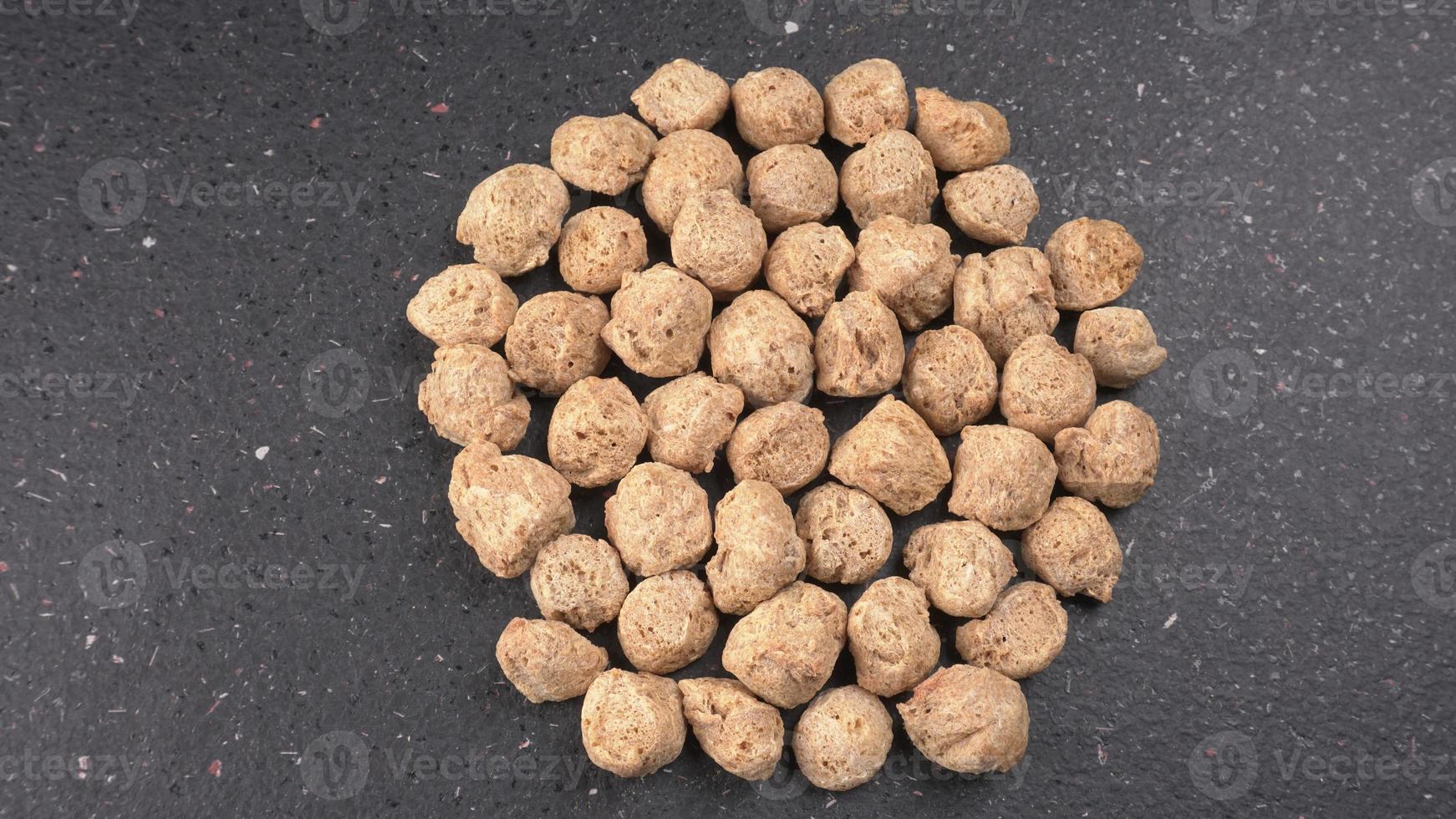 Raw soya chunks on dark background. Healthy, nutritious soybean meat, chunks isolated.Vegan food concept. photo