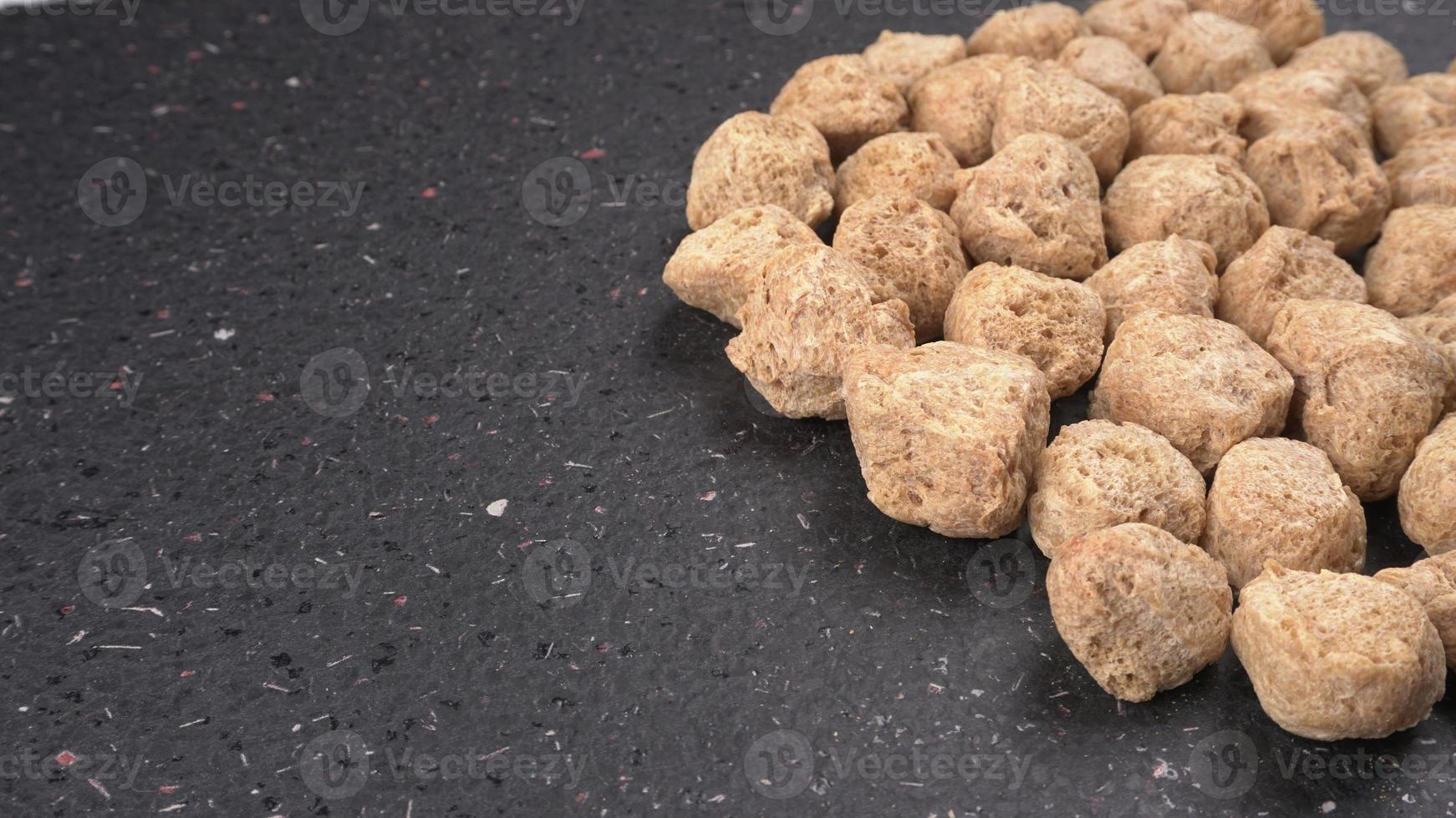 Raw soya chunks on dark background. Healthy, nutritious soybean meat, chunks isolated.Vegan food concept. photo