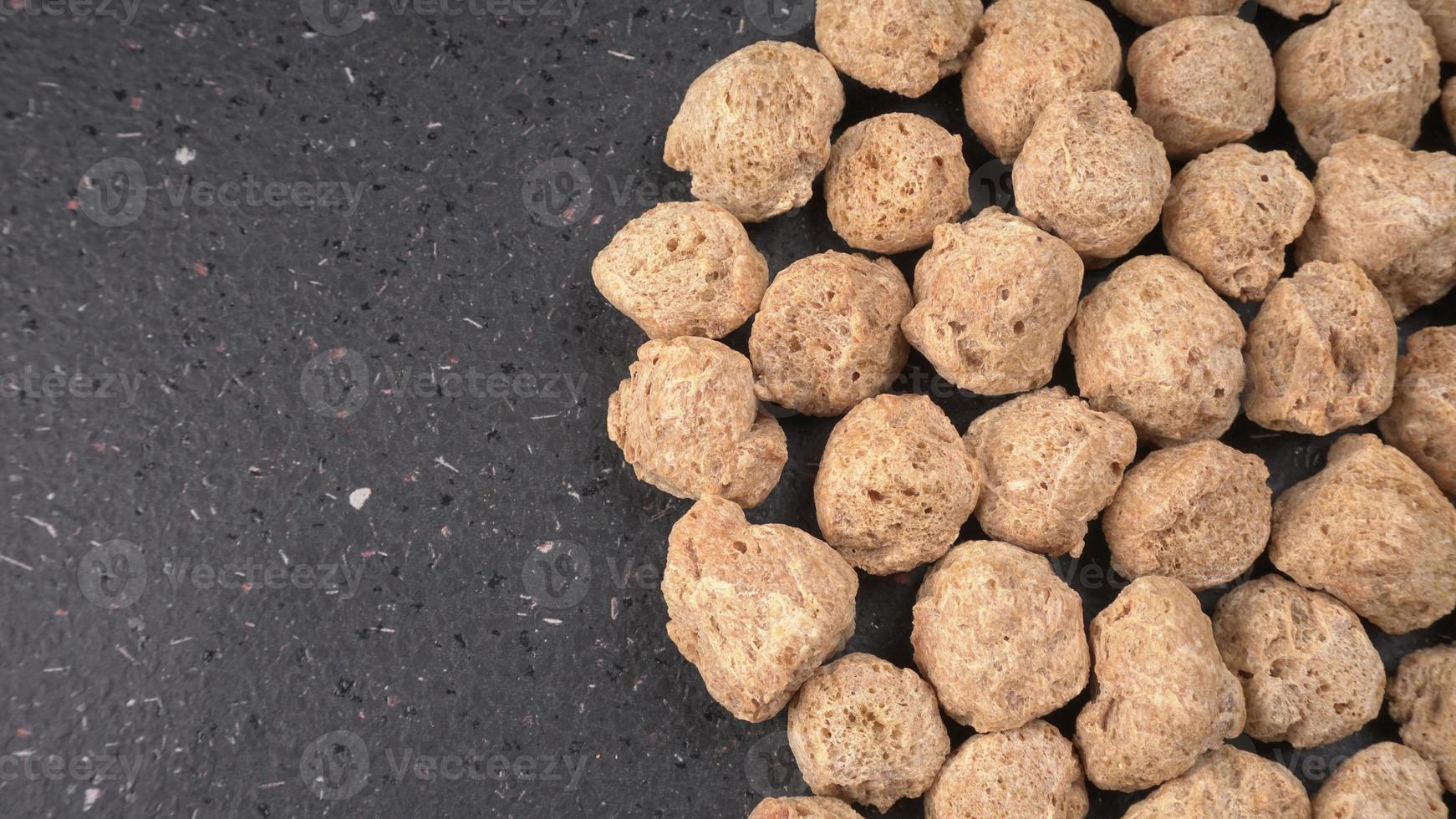 Raw soya chunks on dark background. Healthy, nutritious soybean meat, chunks isolated.Vegan food concept. photo