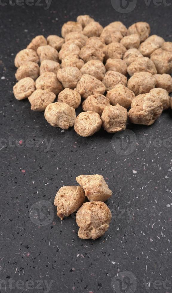 Raw soya chunks on dark background. Healthy, nutritious soybean meat, chunks isolated.Vegan food concept. photo