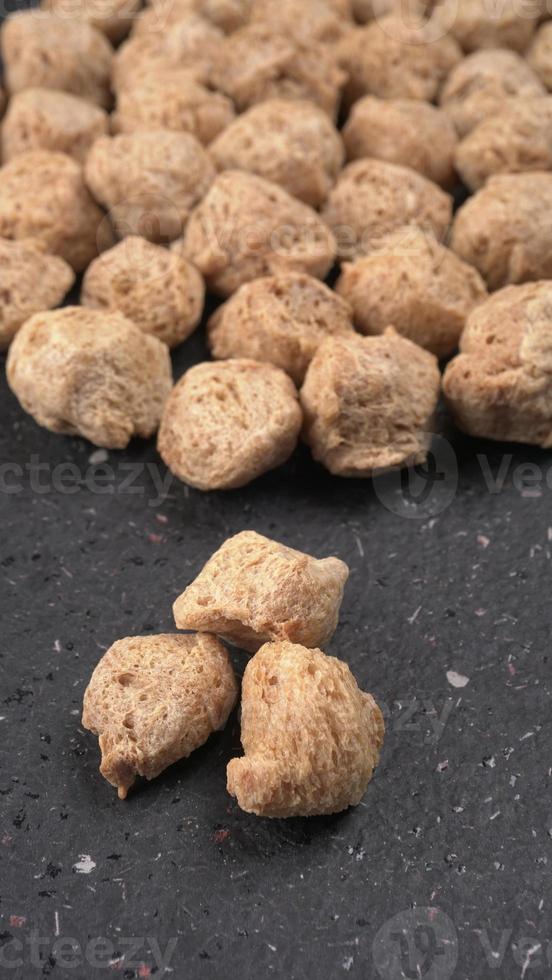 Raw soya chunks on dark background. Healthy, nutritious soybean meat, chunks isolated.Vegan food concept. photo
