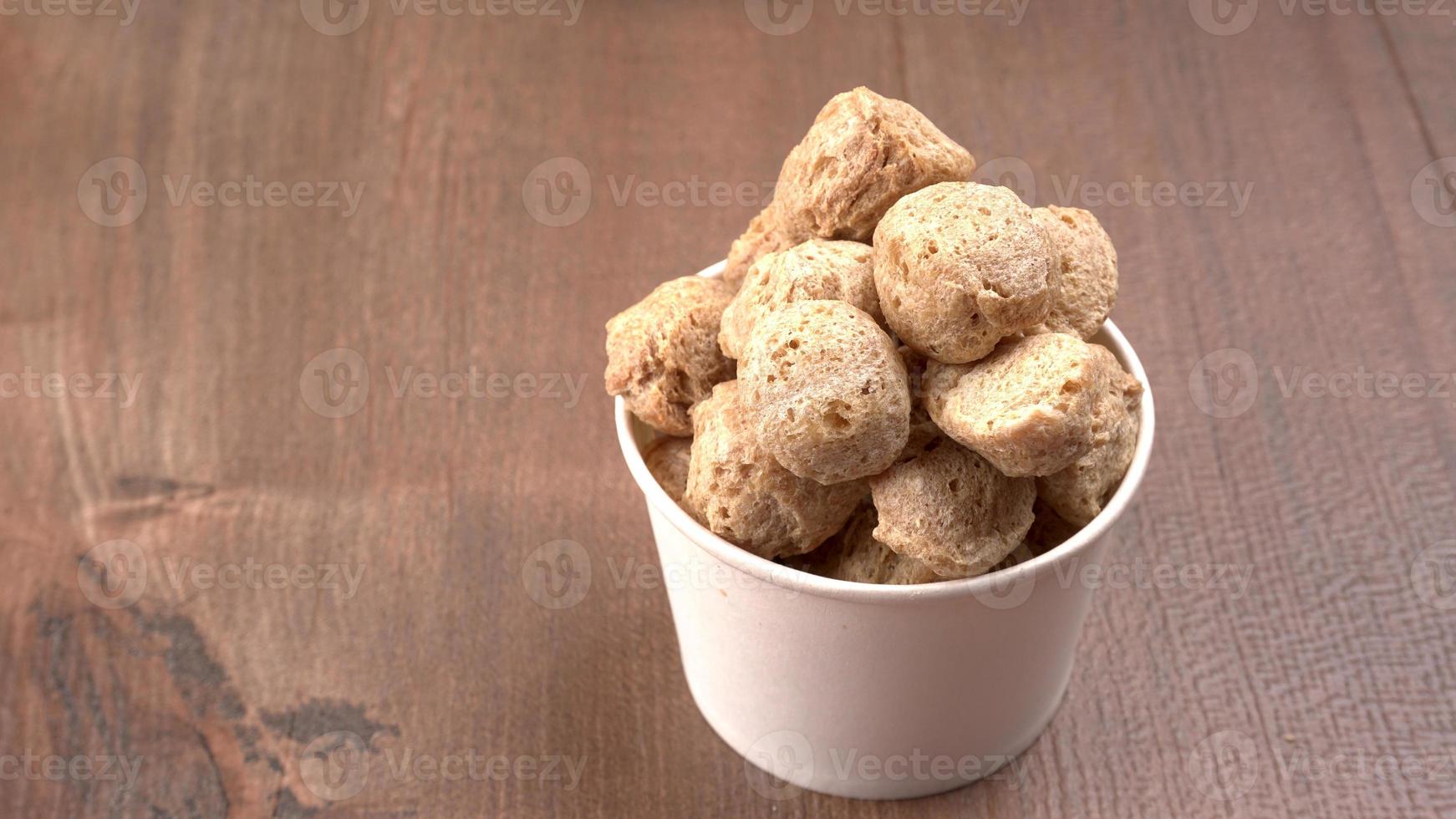 Raw soya chunks on dark background. Healthy, nutritious soybean meat, chunks isolated.Vegan food concept. photo