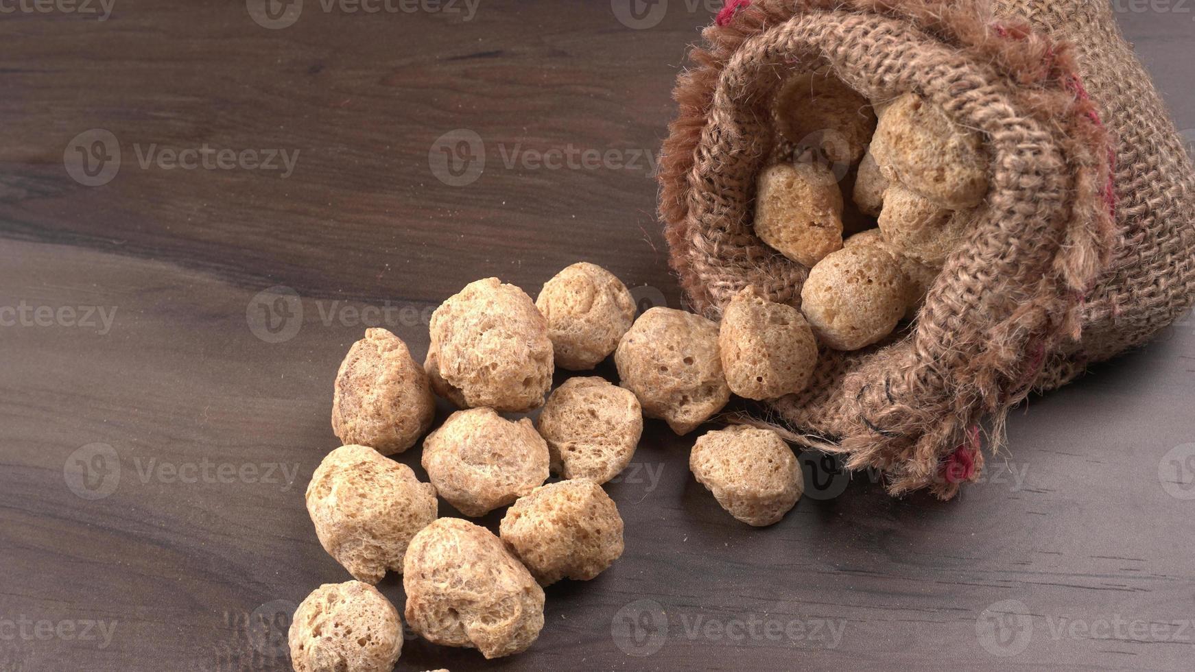 Raw soya chunks on dark background. Healthy, nutritious soybean meat, chunks isolated.Vegan food concept. photo