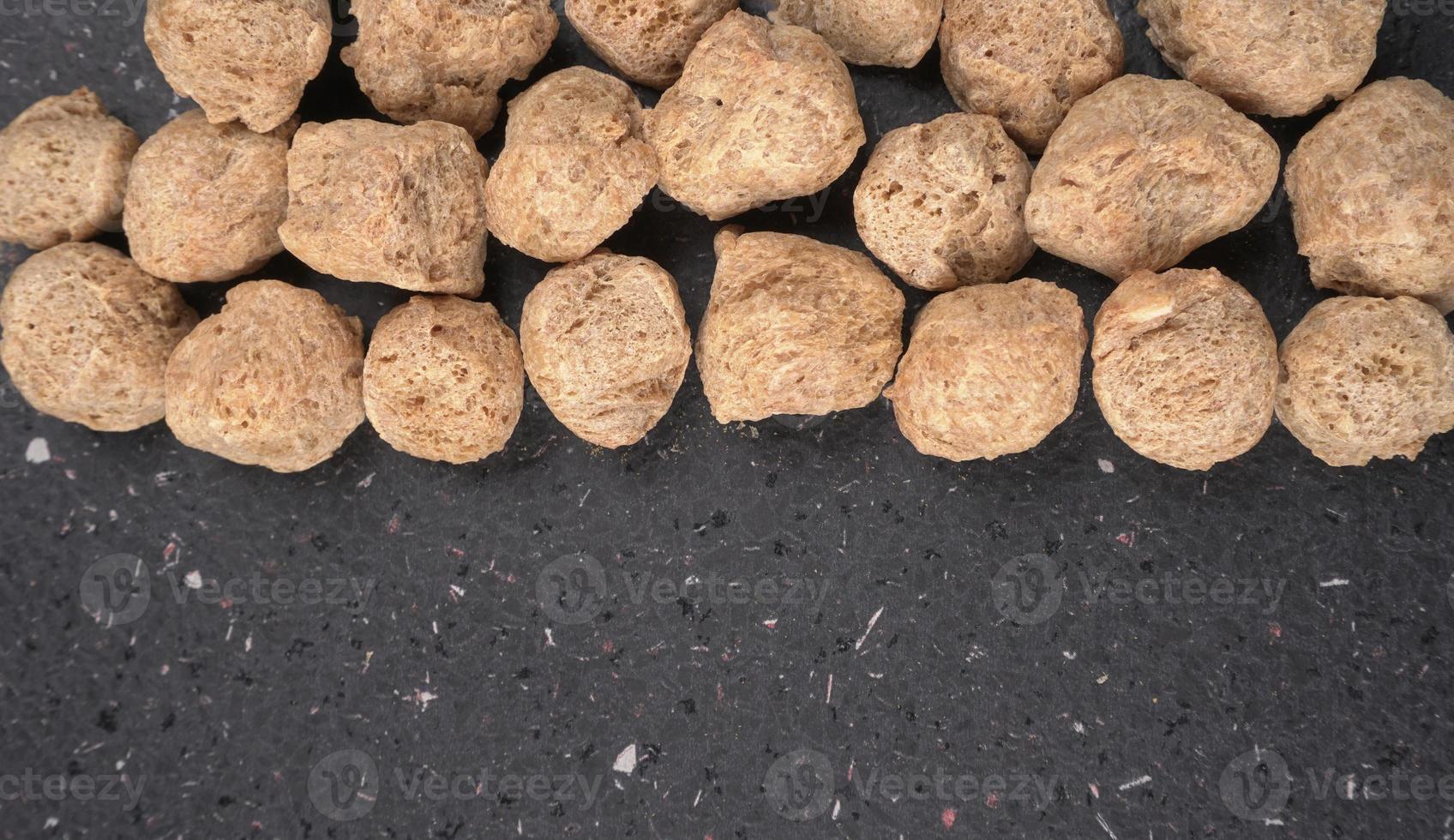 Raw soya chunks on dark background. Healthy, nutritious soybean meat, chunks isolated.Vegan food concept. photo