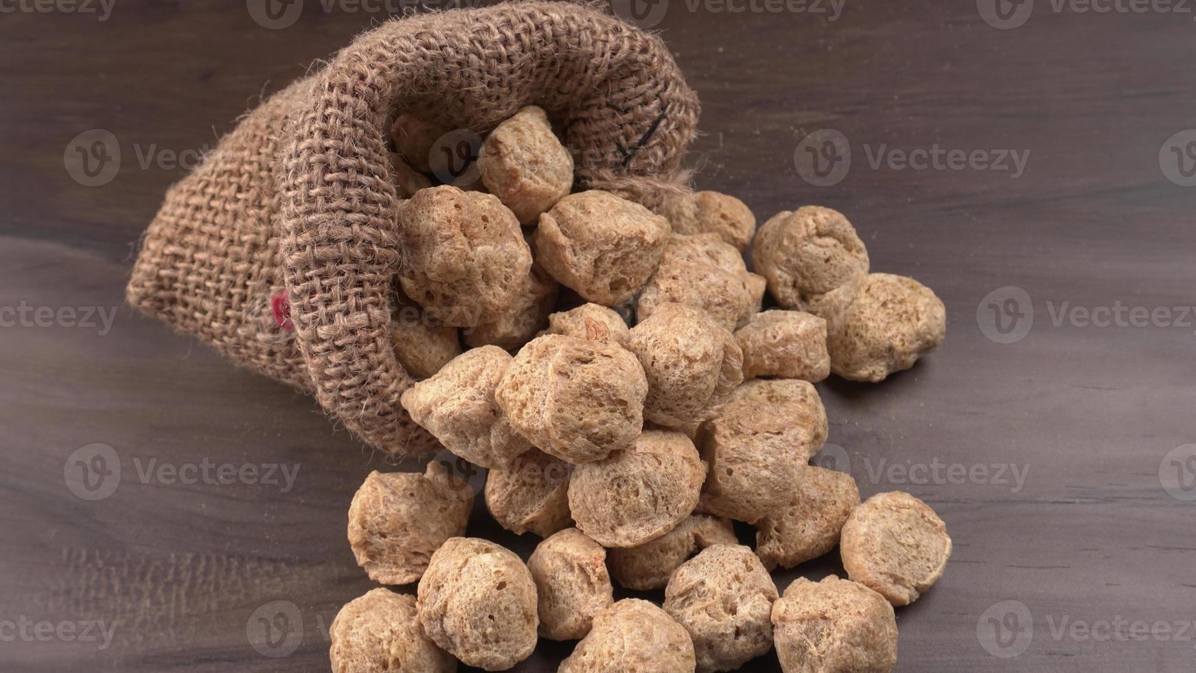 Raw soya chunks on dark background. Healthy, nutritious soybean meat, chunks isolated.Vegan food concept. photo