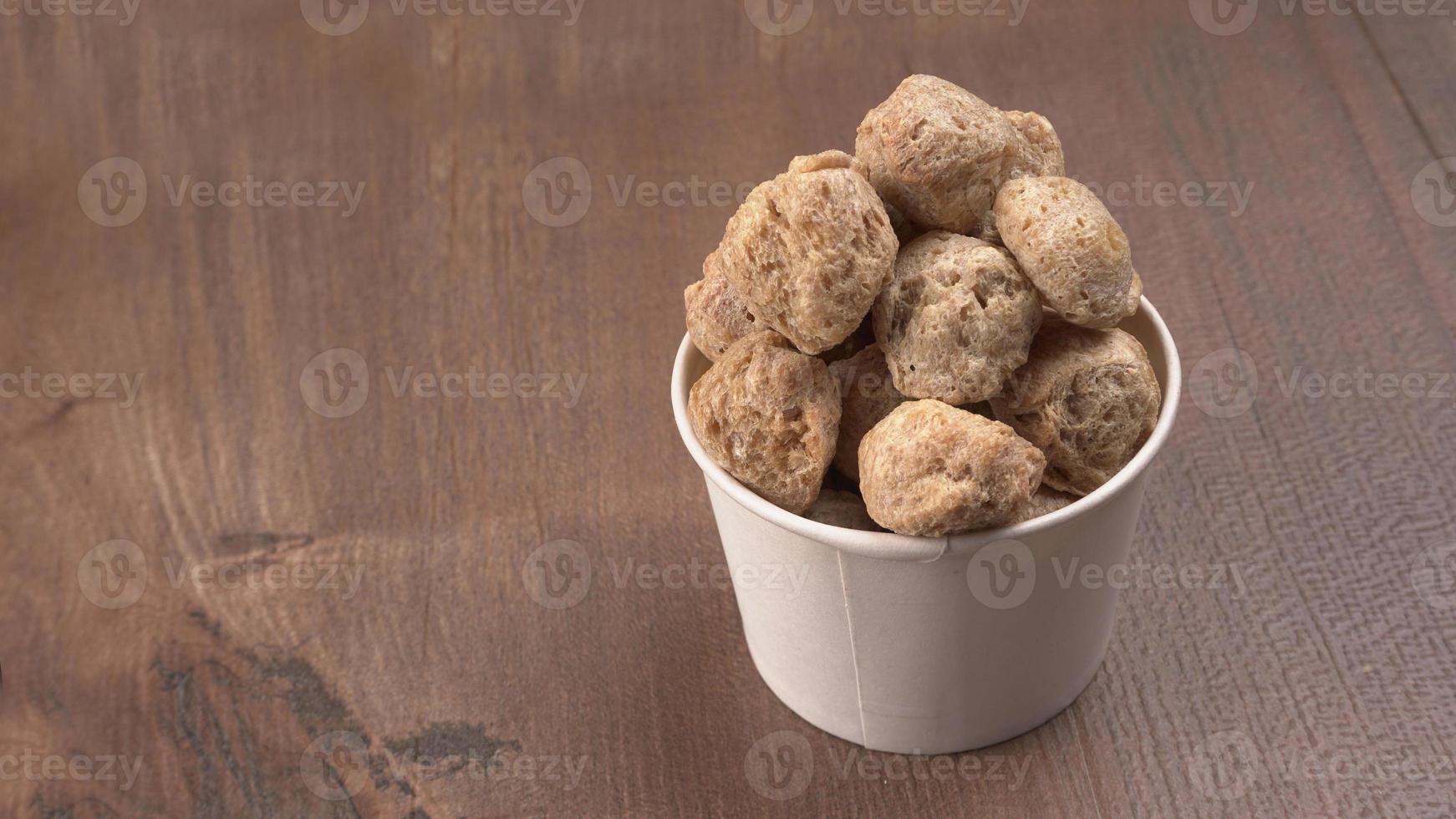 Raw soya chunks on dark background. Healthy, nutritious soybean meat, chunks isolated.Vegan food concept. photo