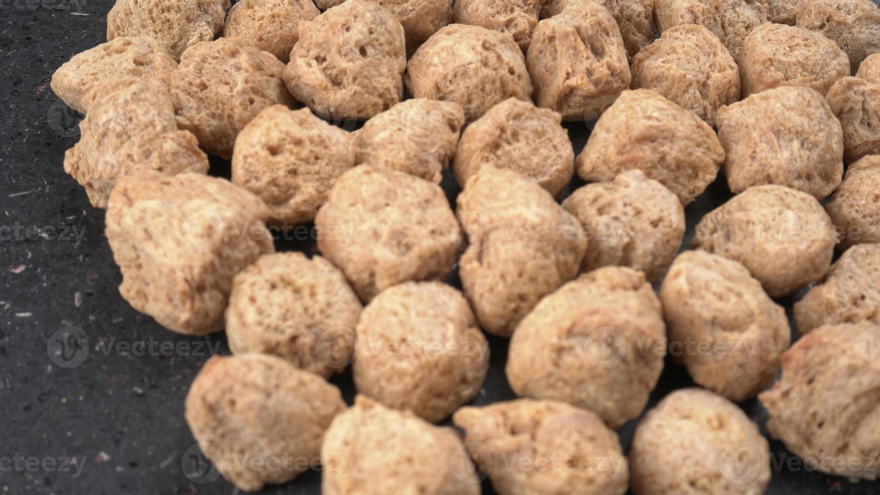 Raw soya chunks on dark background. Healthy, nutritious soybean meat, chunks isolated.Vegan food concept. photo