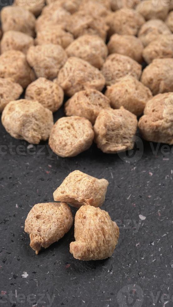 Raw soya chunks on dark background. Healthy, nutritious soybean meat, chunks isolated.Vegan food concept. photo