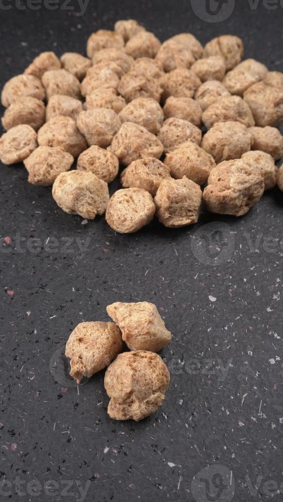 Raw soya chunks on dark background. Healthy, nutritious soybean meat, chunks isolated.Vegan food concept. photo