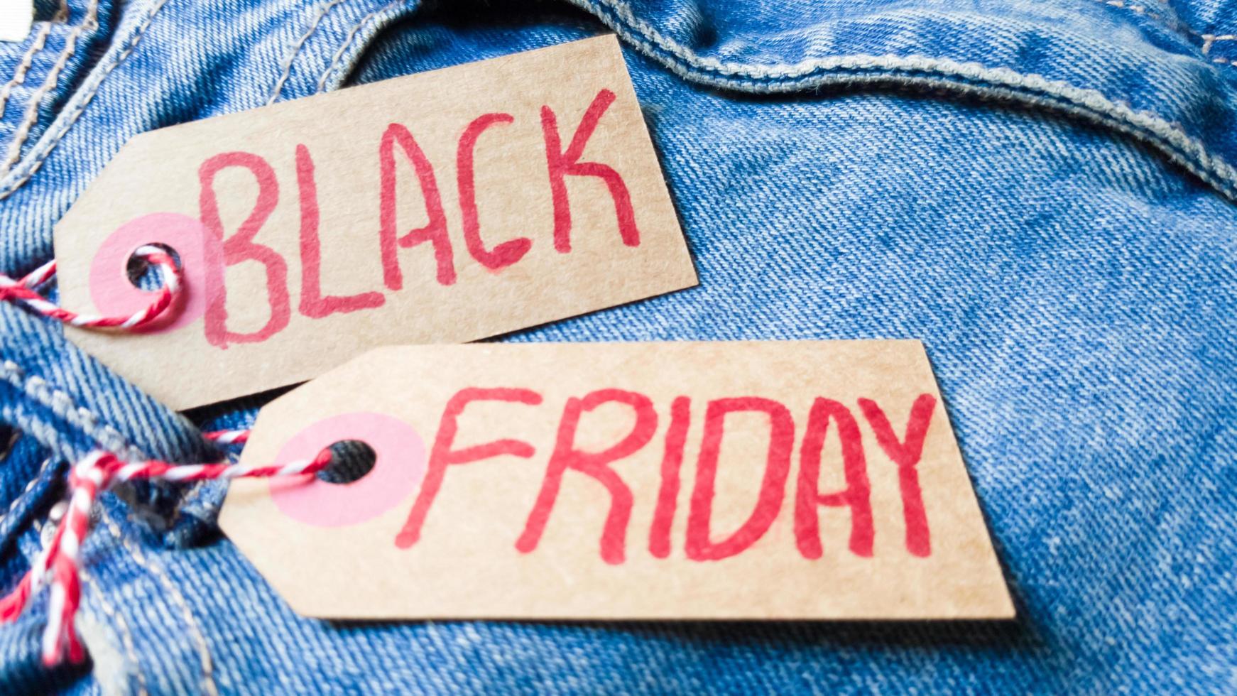 Stylish jeans with a black friday flag. Black friday and cyber monday sale discount concept tag with blue jeans. Black friday written on grunge jeans texture. Background, holiday concept. Black Friday photo