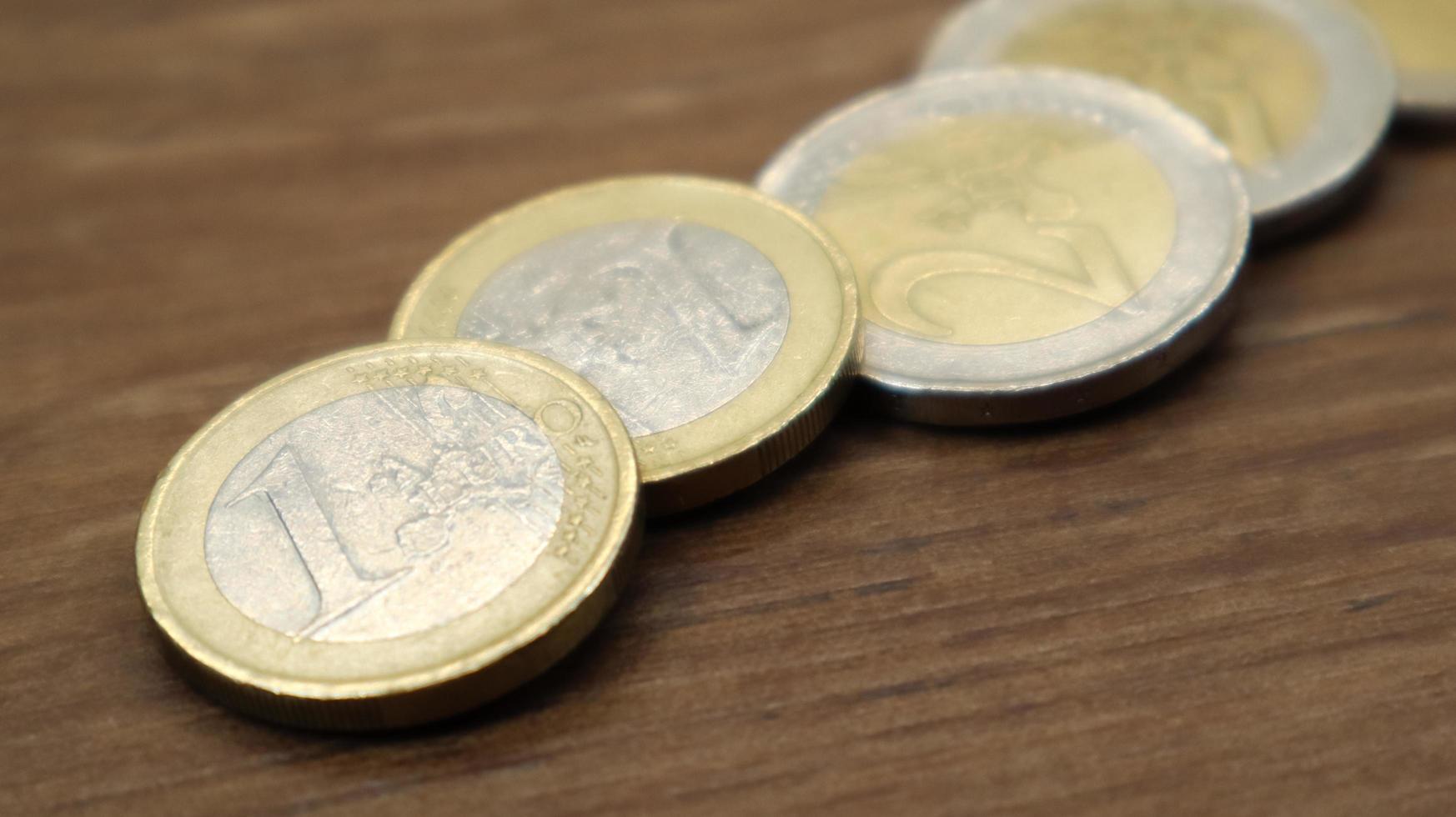 monedas brillantes de un euro yacen sobre la mesa. moneda de la unión europea. foto